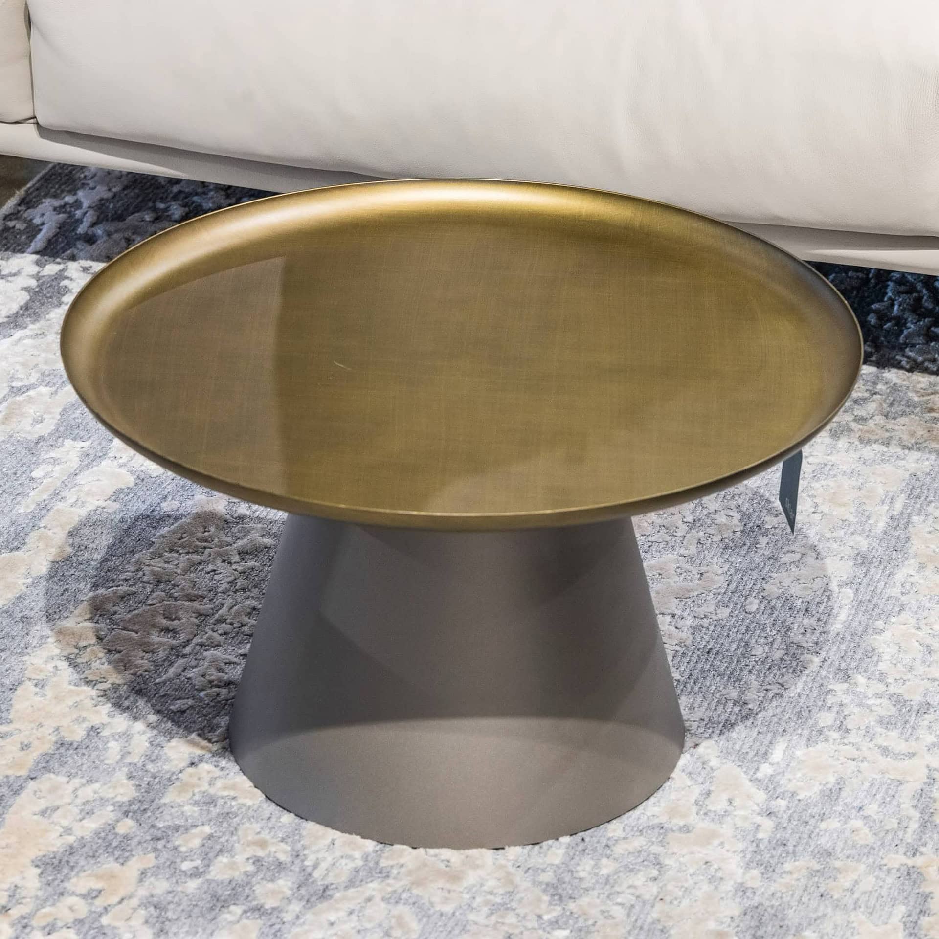 Modern metallic accent table with gold top and sculptural gray base for stylish home decor.
