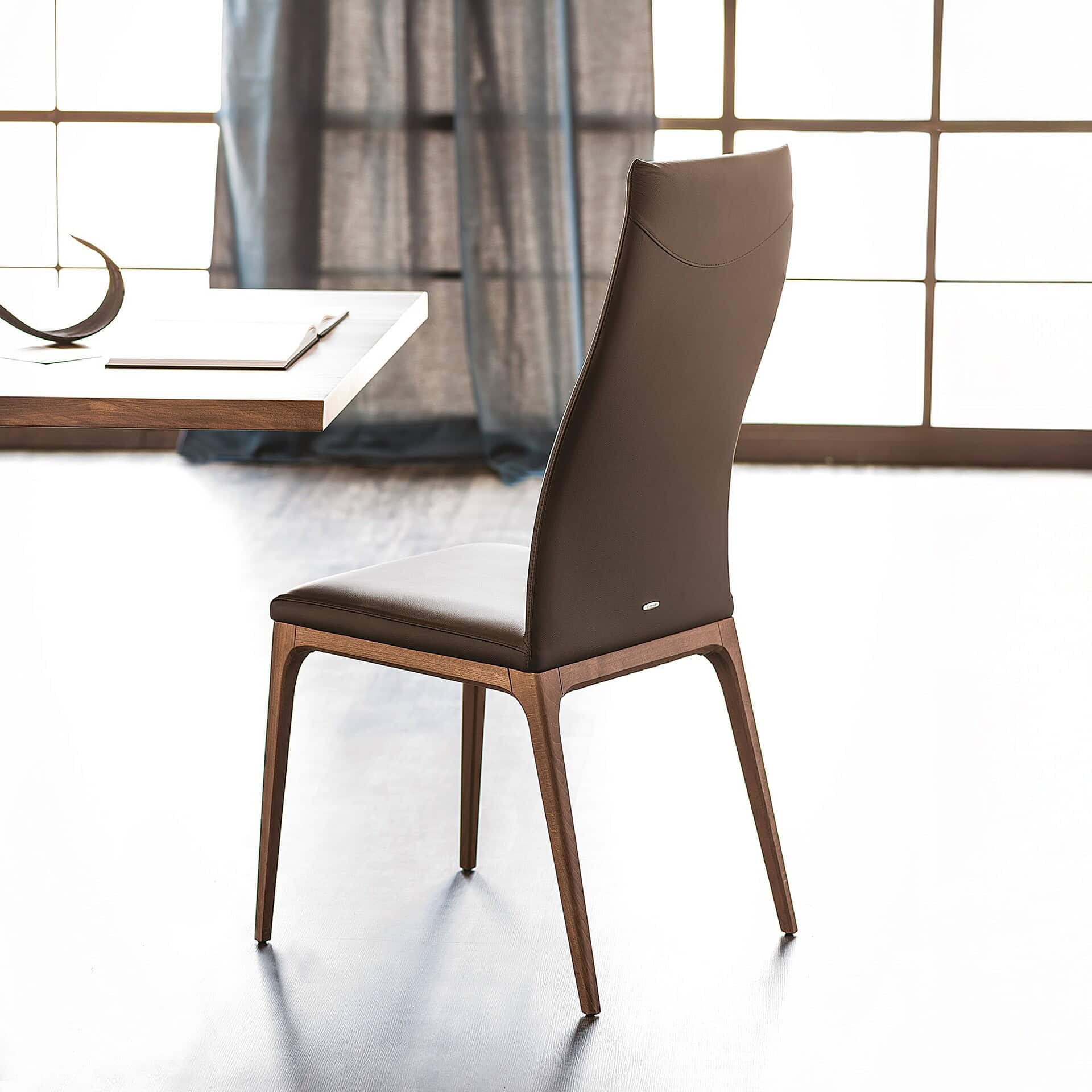 Back view of the Arcadia High Back Dining Chair showcasing its sleek upholstered design and tapered wooden legs.
