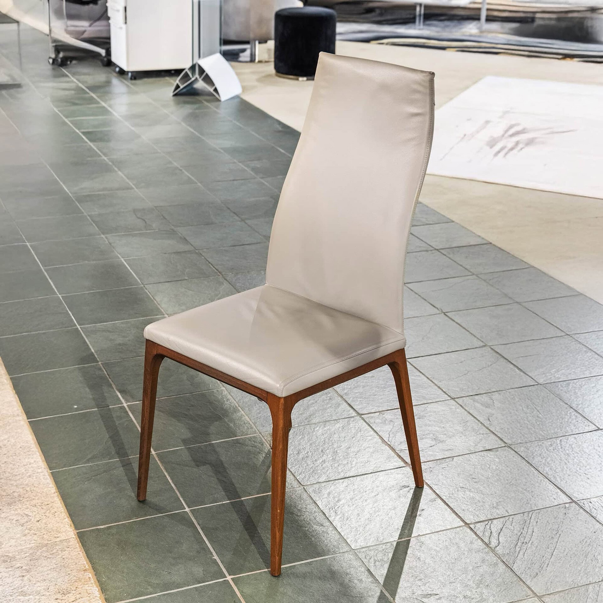 Elegant beige leather dining chair with wooden legs, perfect for modern home interiors.