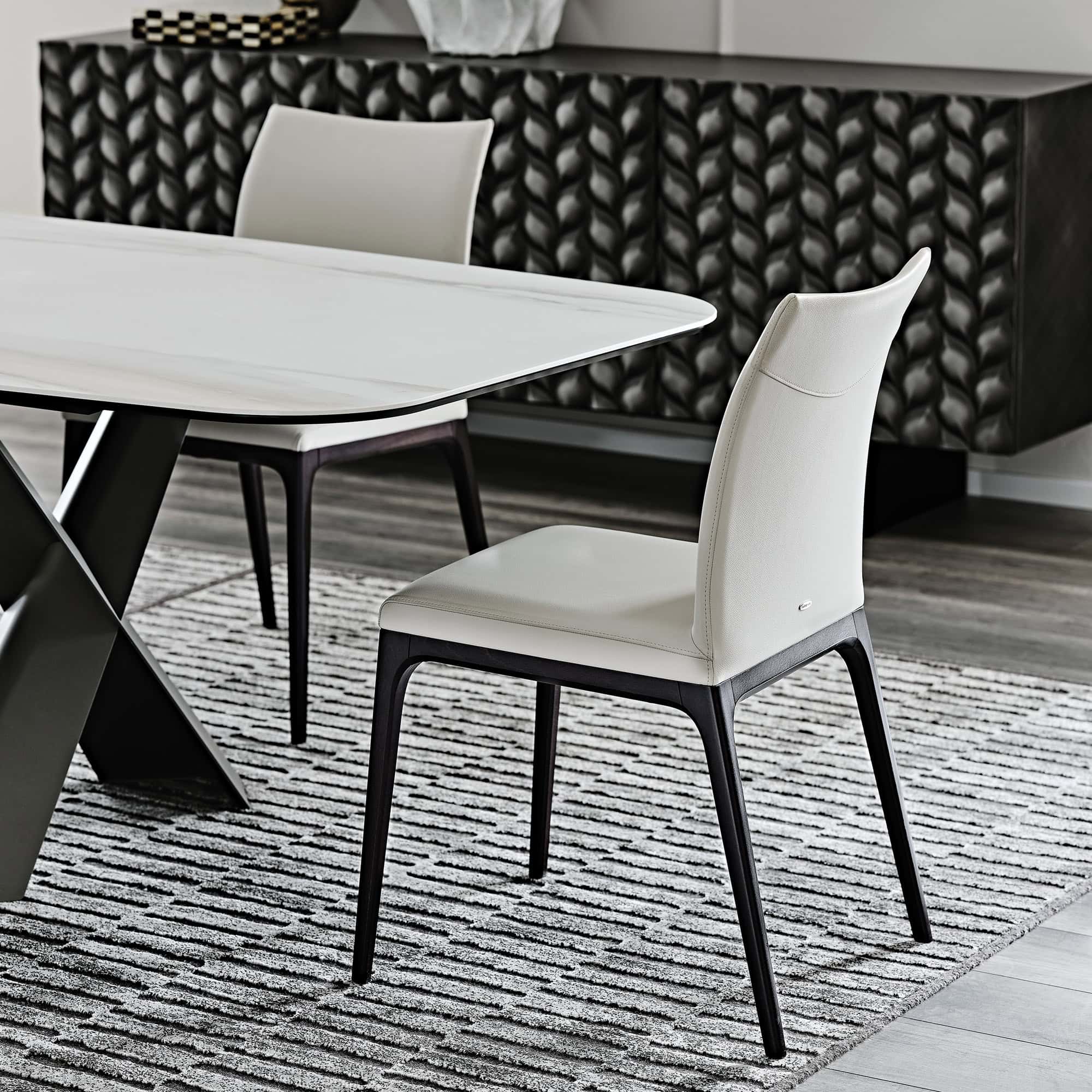 Arcadia Low Back Dining Chairs, upholstered in light leather with dark wood legs, styled in monochrome dining interior
