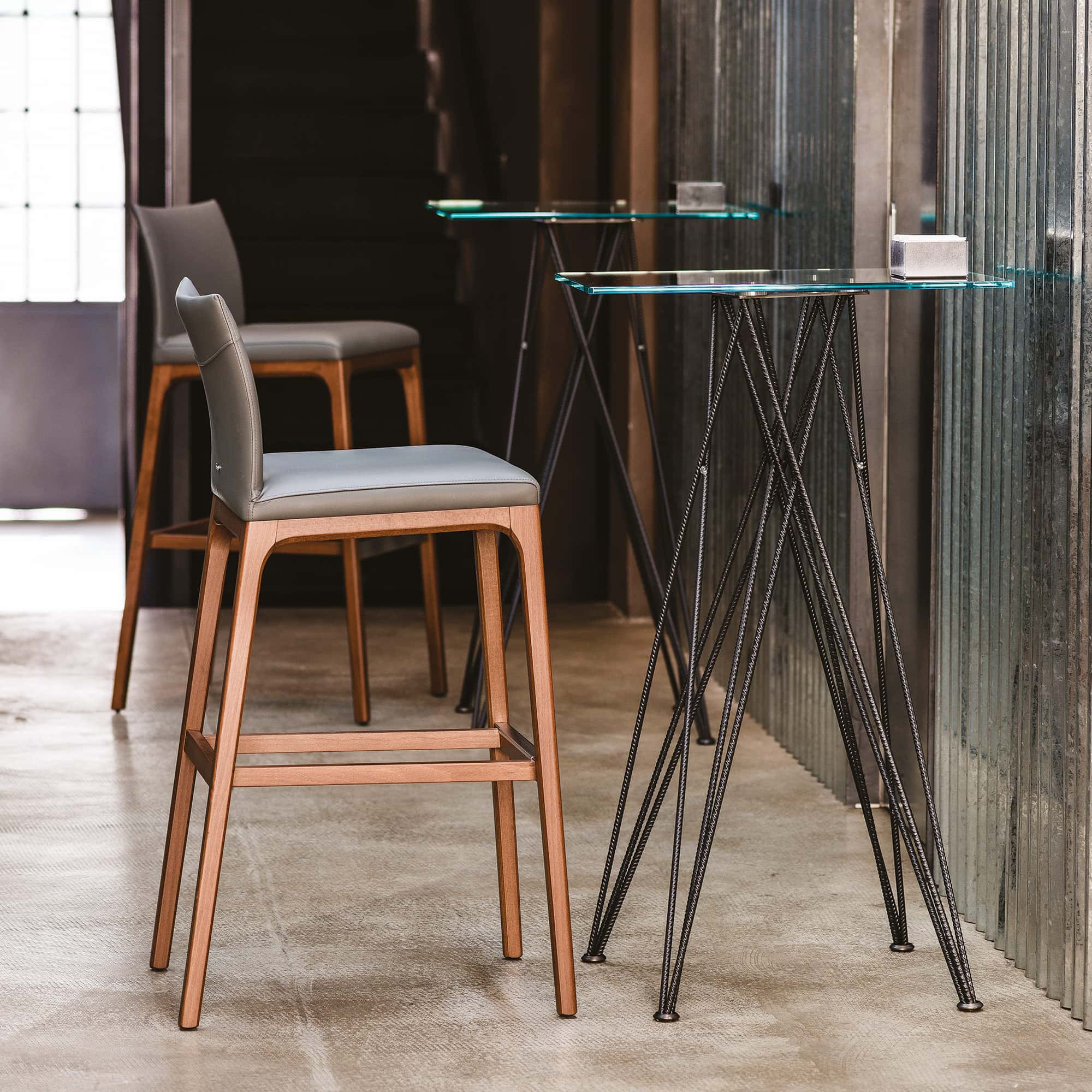Arcadia Stool in a dining setting with natural wood frame and upholstered seat.