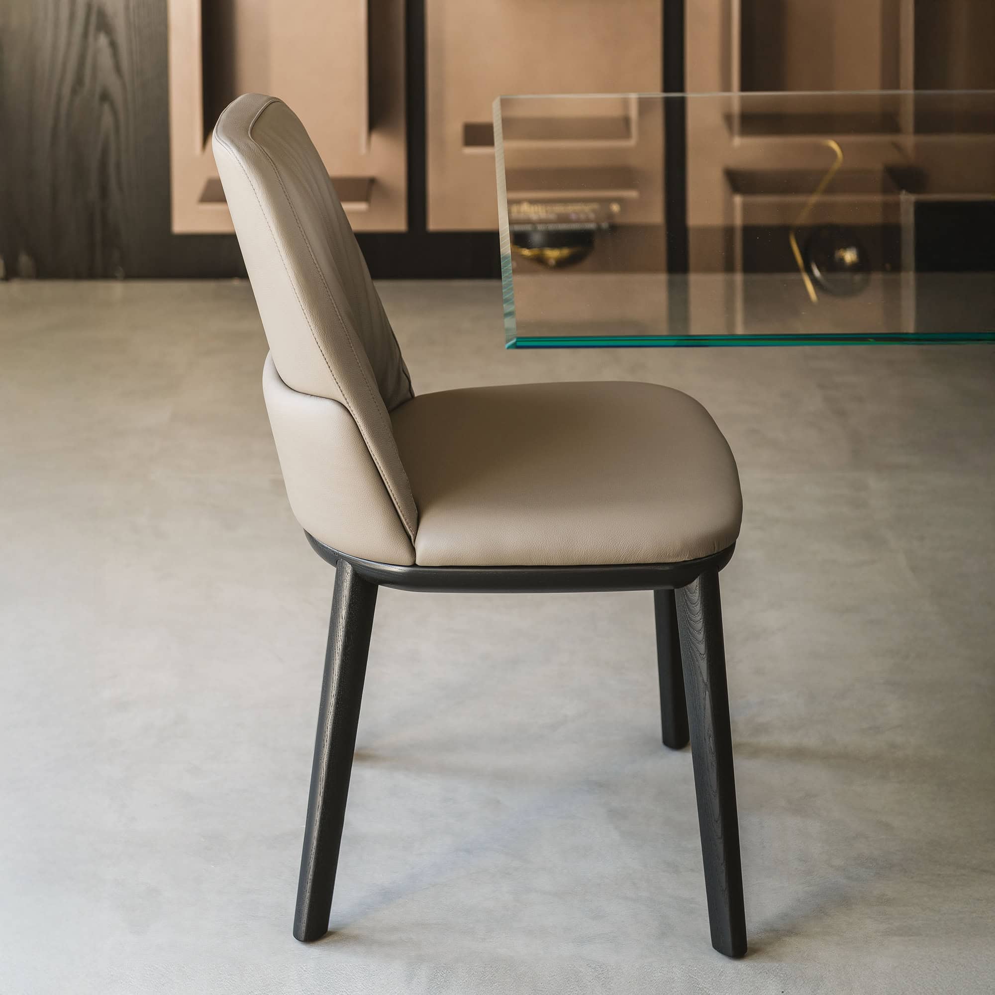 Angled view of the Belinda Dining Chair upholstered in beige leather with dark legs.
