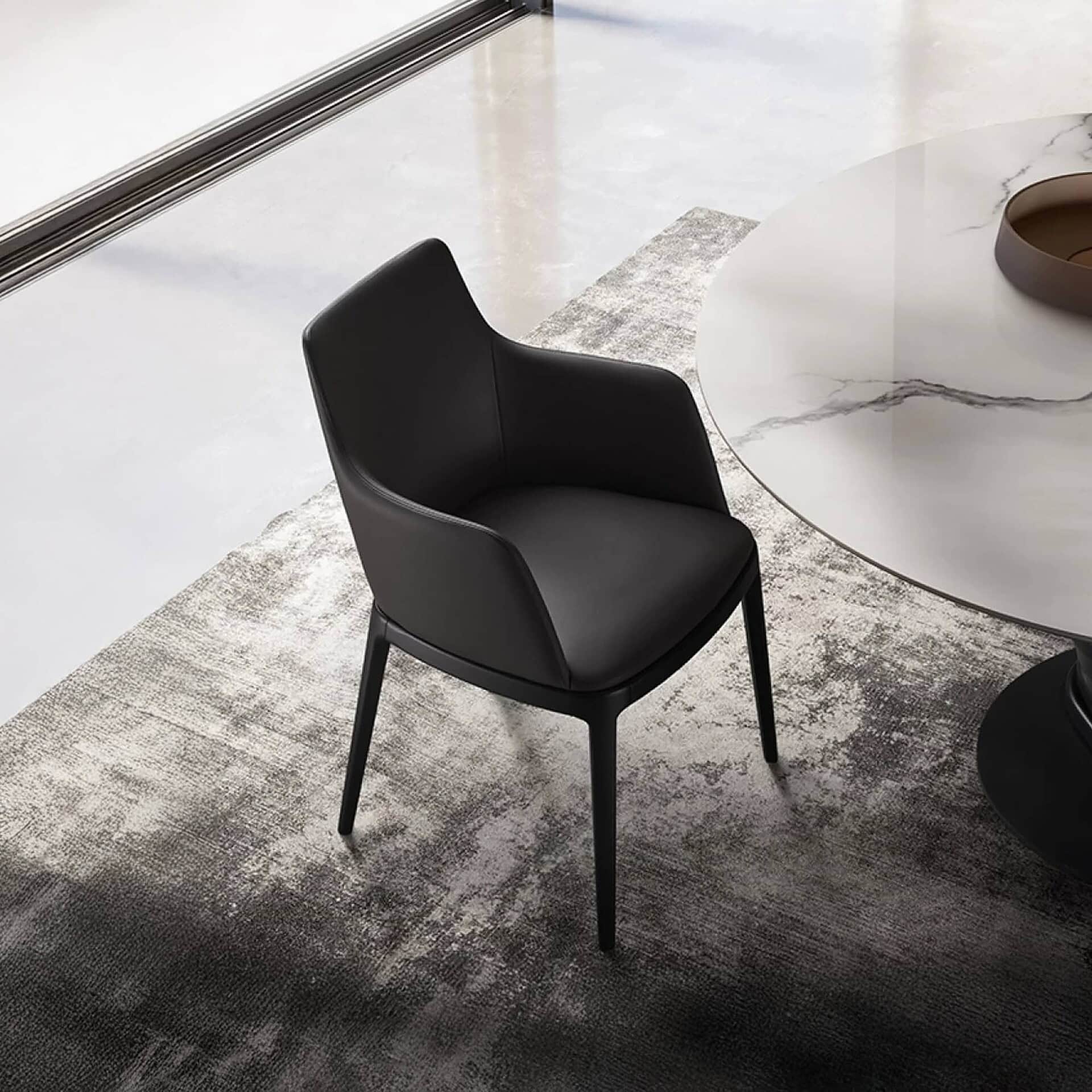 Contemporary black dining chair with sleek leather upholstery and minimalist design.