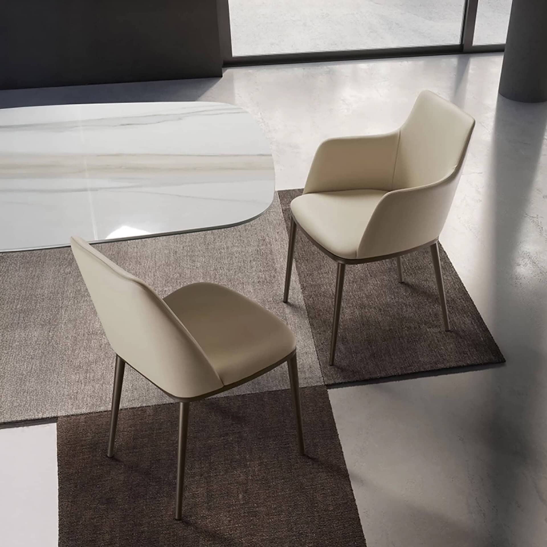 Contemporary dining chairs in beige with sleek metal legs on a textured rug.