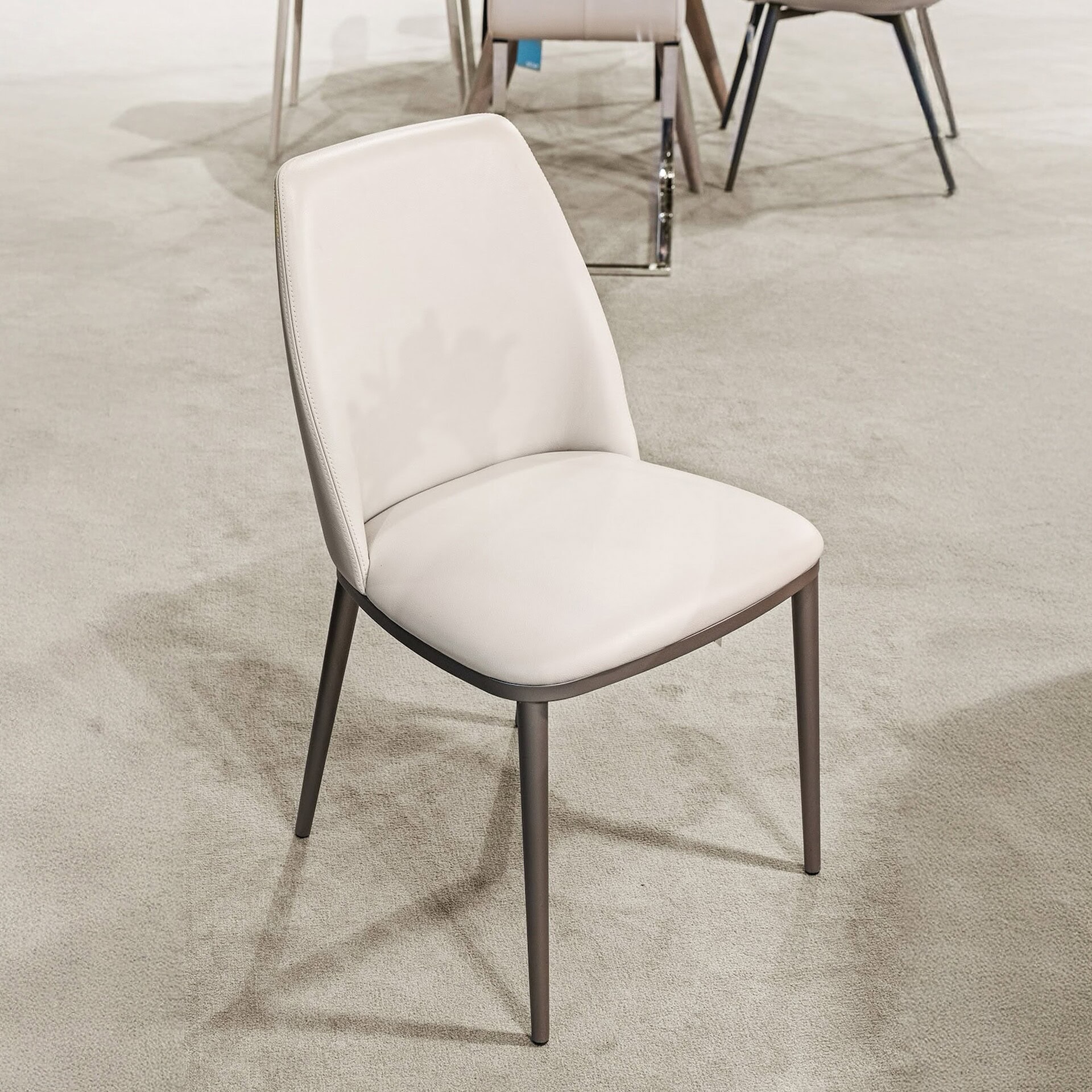 Modern white upholstered dining chair with metal legs for contemporary home and restaurant decor.