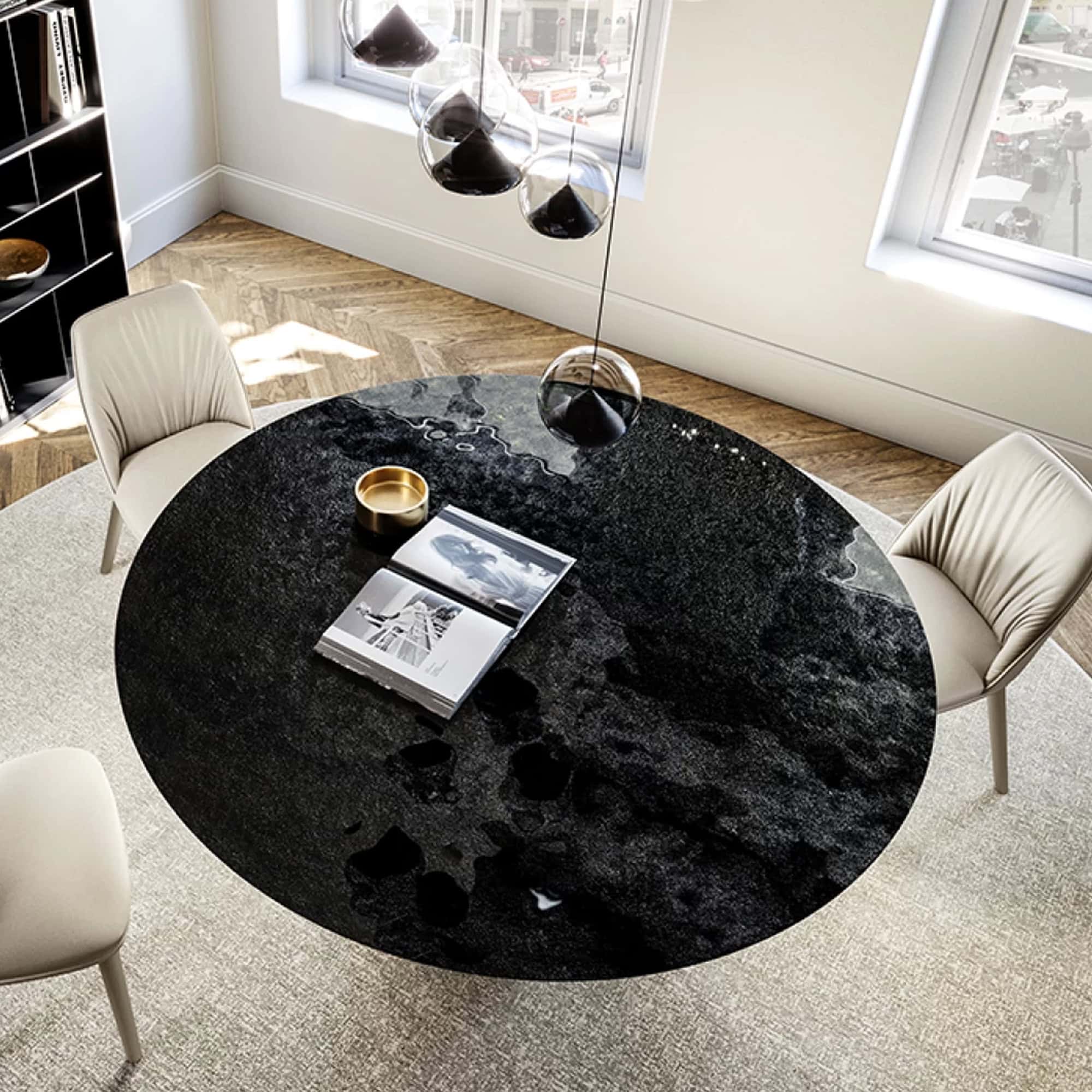 Black marble dining table with white chairs and modern pendant lighting.