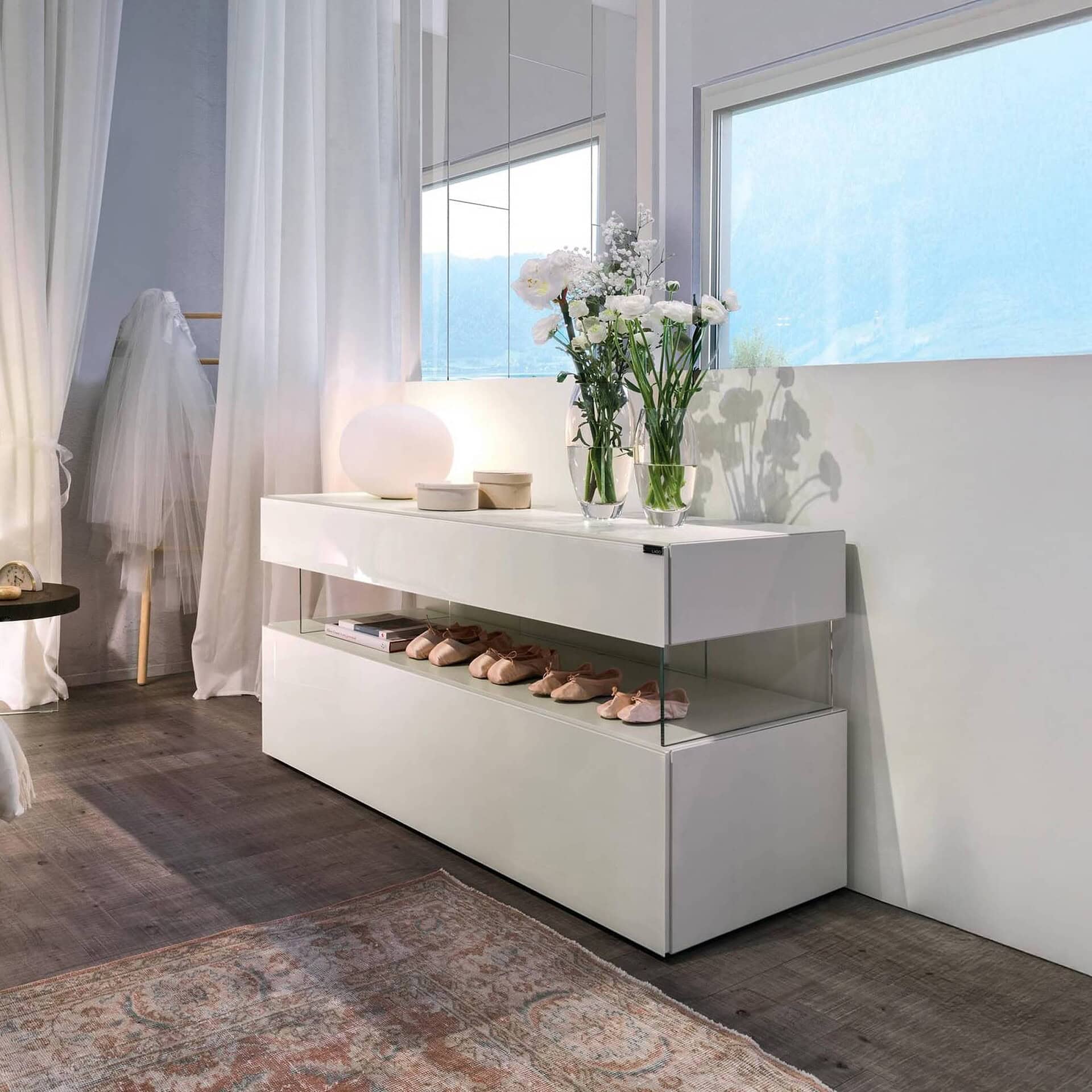 Air Dresser 0677 in white lacquer with glass legs, styled in a bright bedroom with flowers on top.