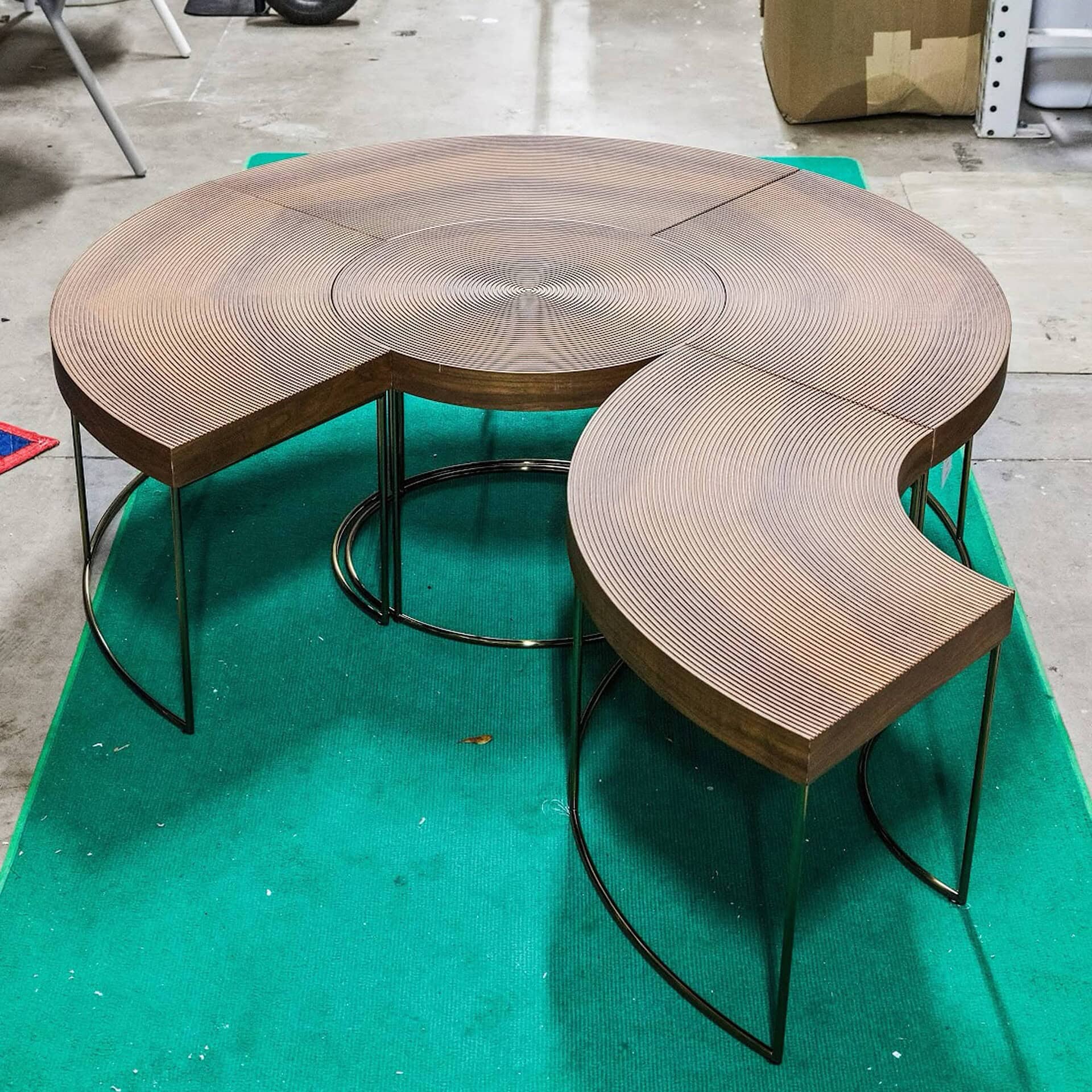 Contemporary wooden dining table with curved design and black metal legs, modern furniture by Sklar Furnishings.