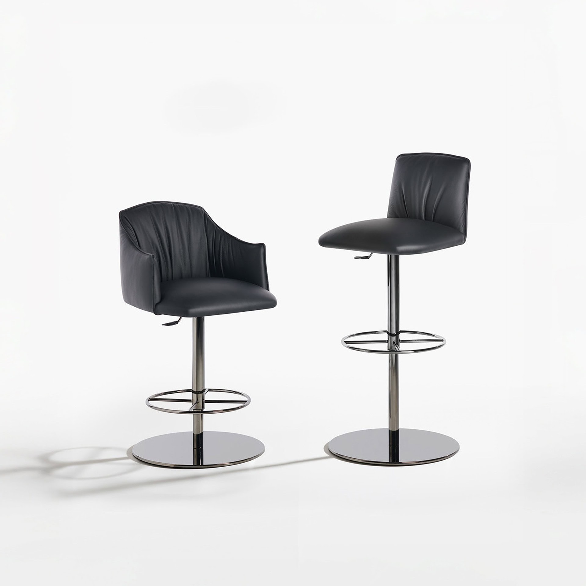 Pair of Blossom stools with round pedestal bases, one with armrests and one without, shown against a white background.