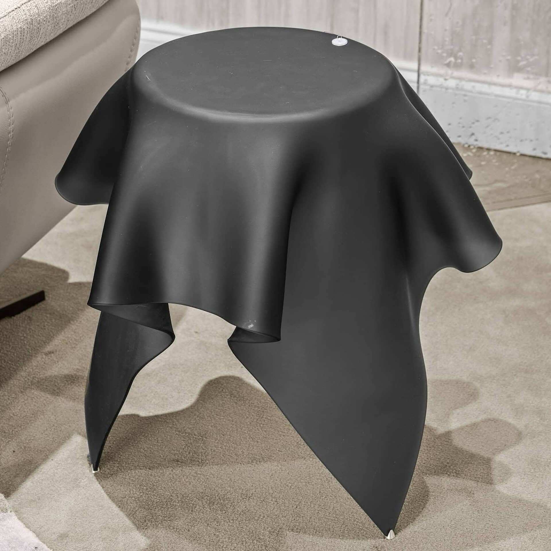 Sleek black side table with draped fabric-inspired design, modern furniture accent for stylish interiors.
