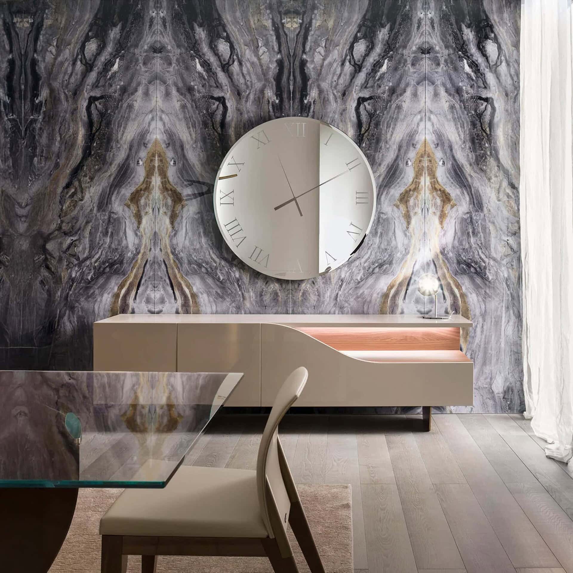 Dining room setting featuring the Segno Buffet with a round mirror above and marble wall backdrop.