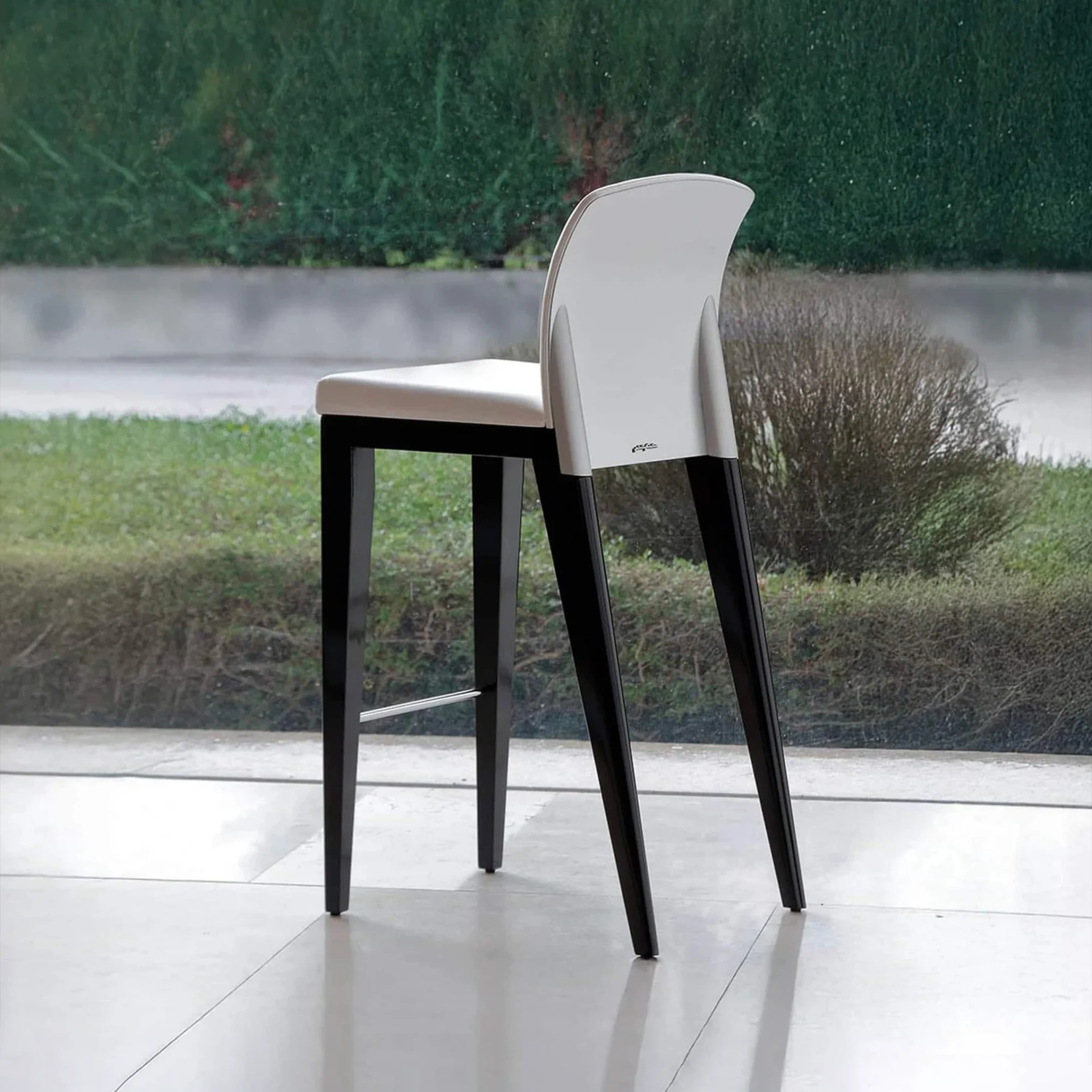 Contemporary bar stool with white seat and black legs for kitchen or bar area.