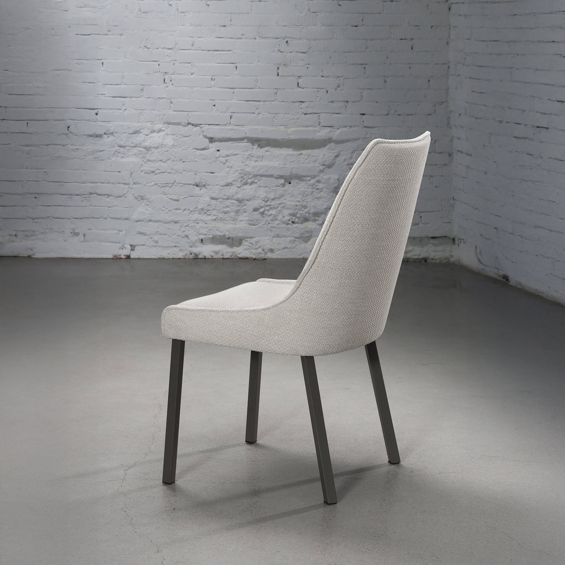 Side view of the Trica Olivia Chair in a light fabric finish, showcasing its gently sloped back and solid wood legs.