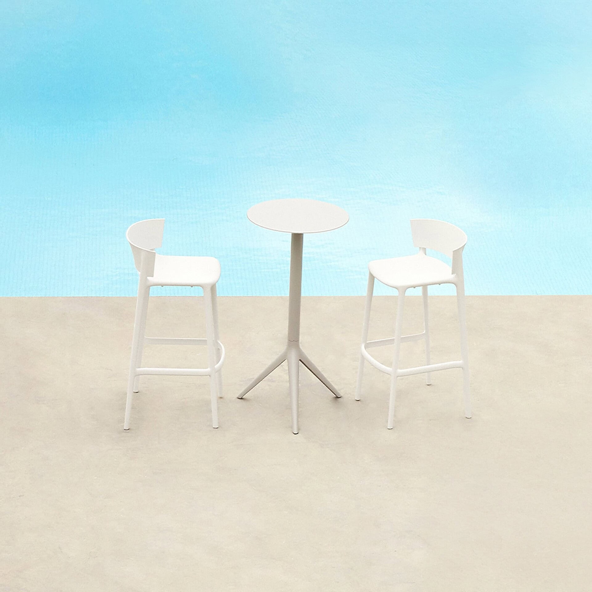 Africa Bar Stools in white finish arranged poolside with matching tables in a minimal outdoor setting.