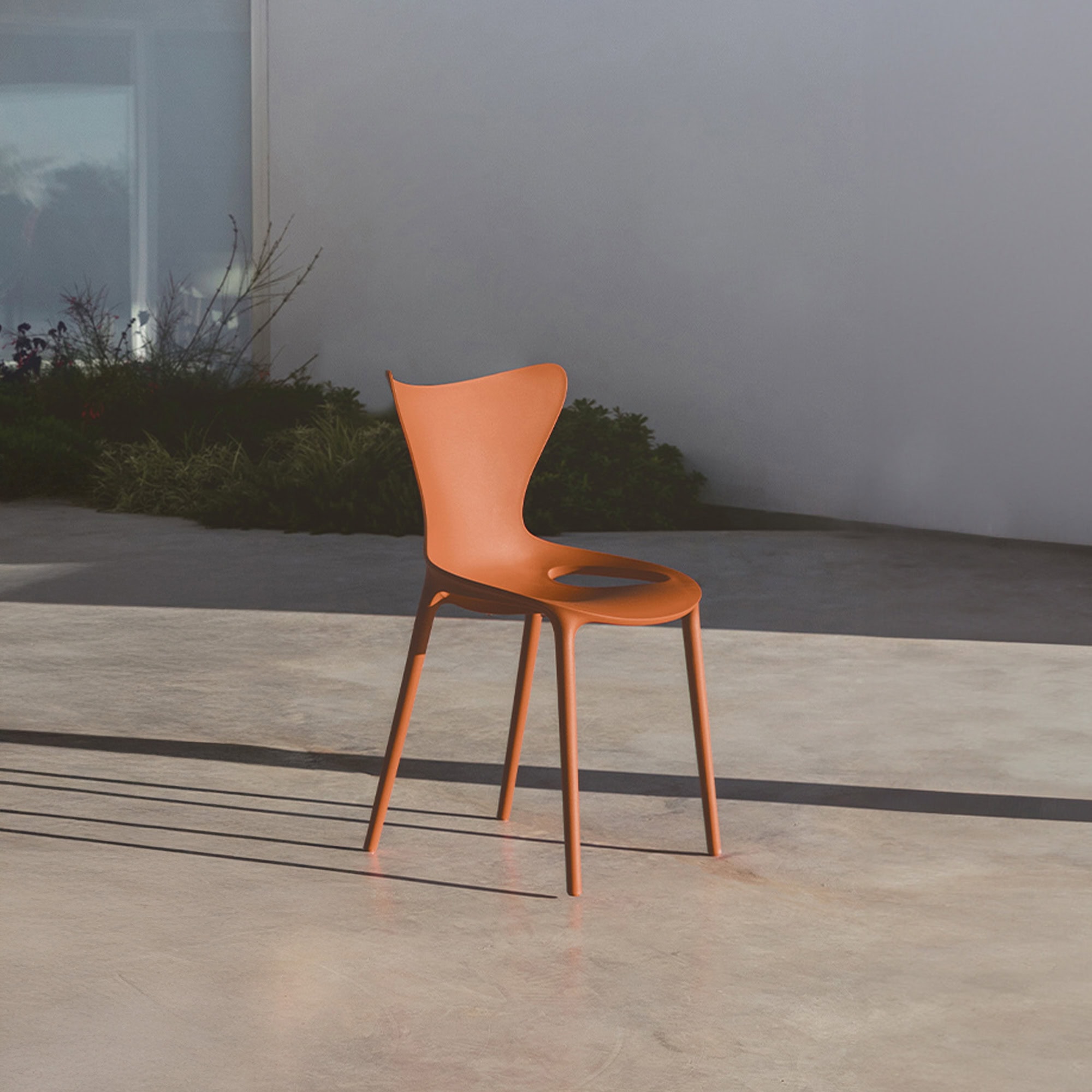 Vondom Love Chair in orange, shown outdoors on a minimalist patio setting.
