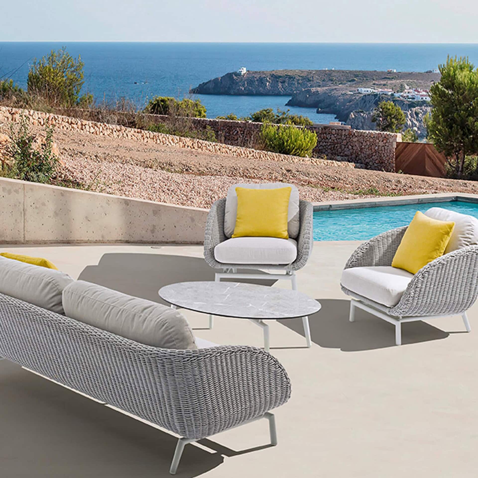 Scoop Coffee Table styled poolside with matching outdoor seating set, overlooking ocean view.