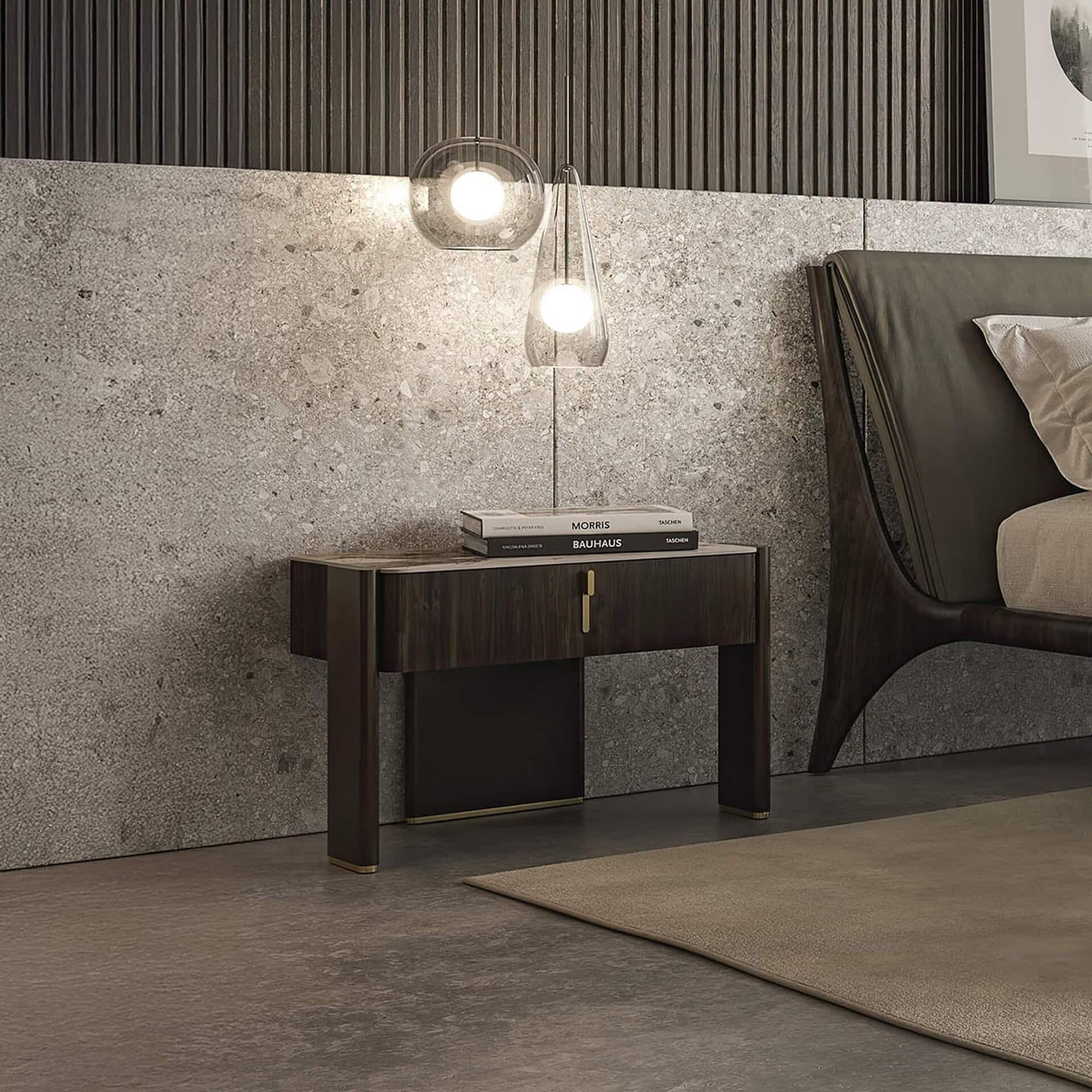 Front view of Julian 1-Drawer Nightstand placed beside a bed, featuring a marble top and bronze frame against a concrete wall.