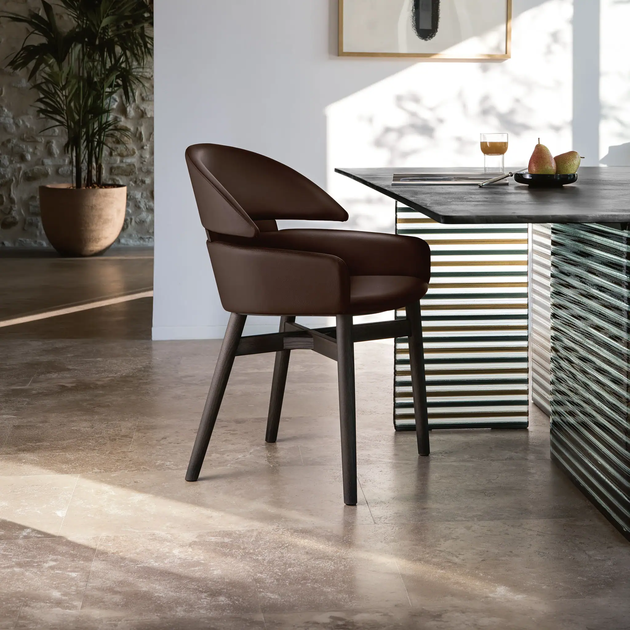 Modern Lloyd dining chair in brown leather with black wooden legs.