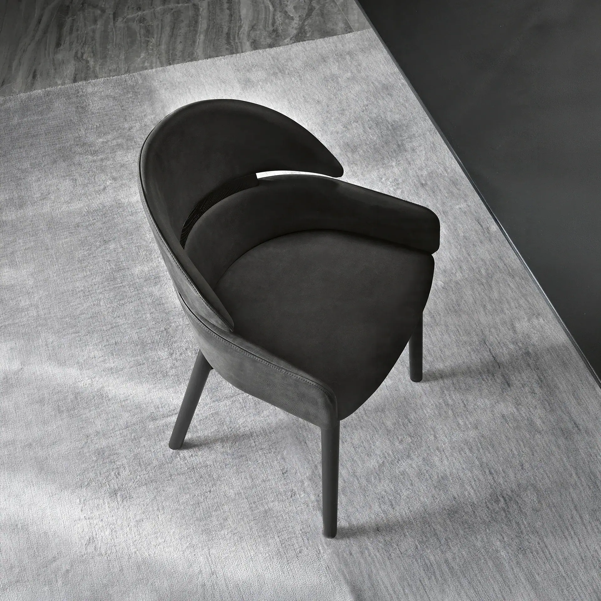 Modern black Lloyd dining chair with curved back and armrest.