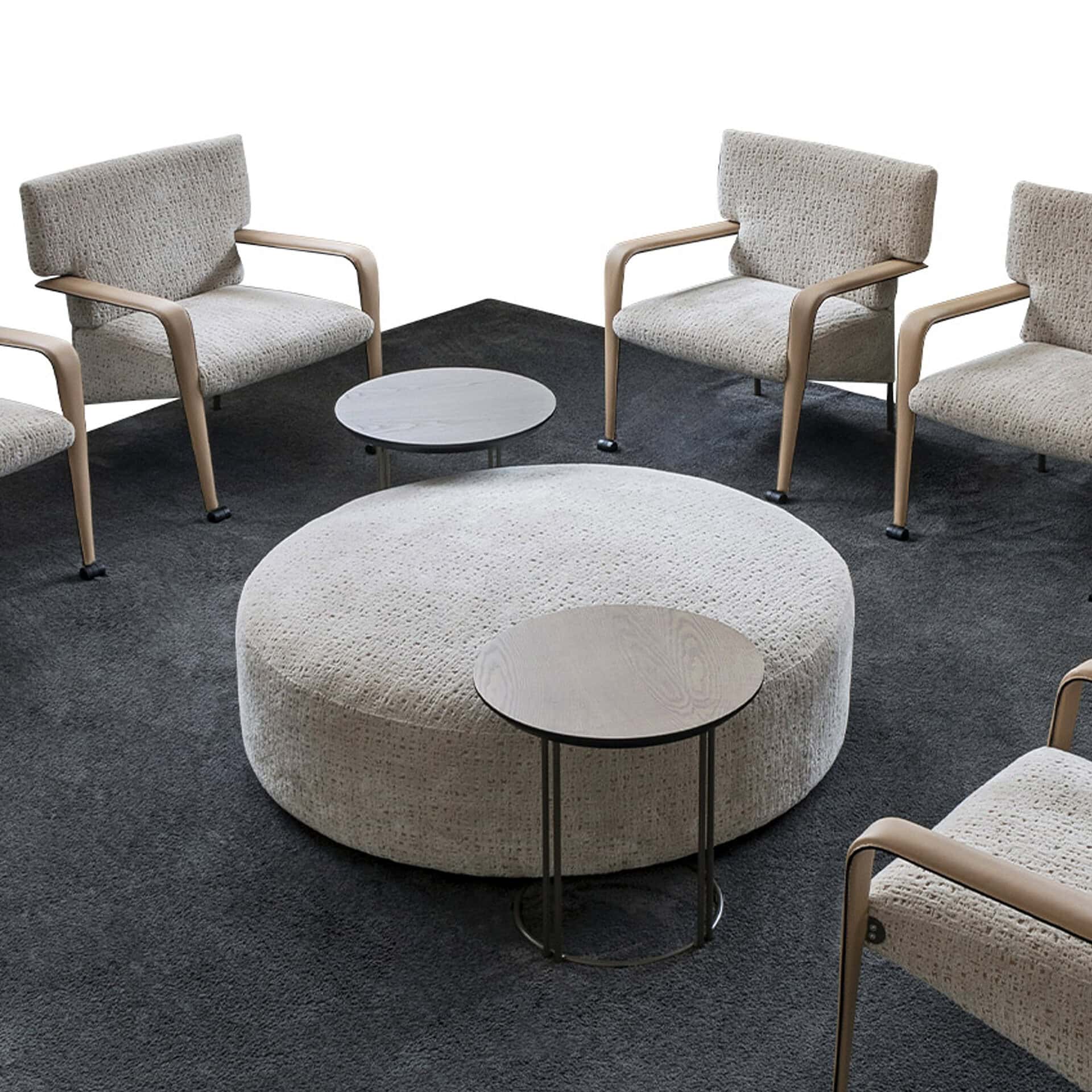 Contemporary waiting room furniture with round ottoman and side tables.