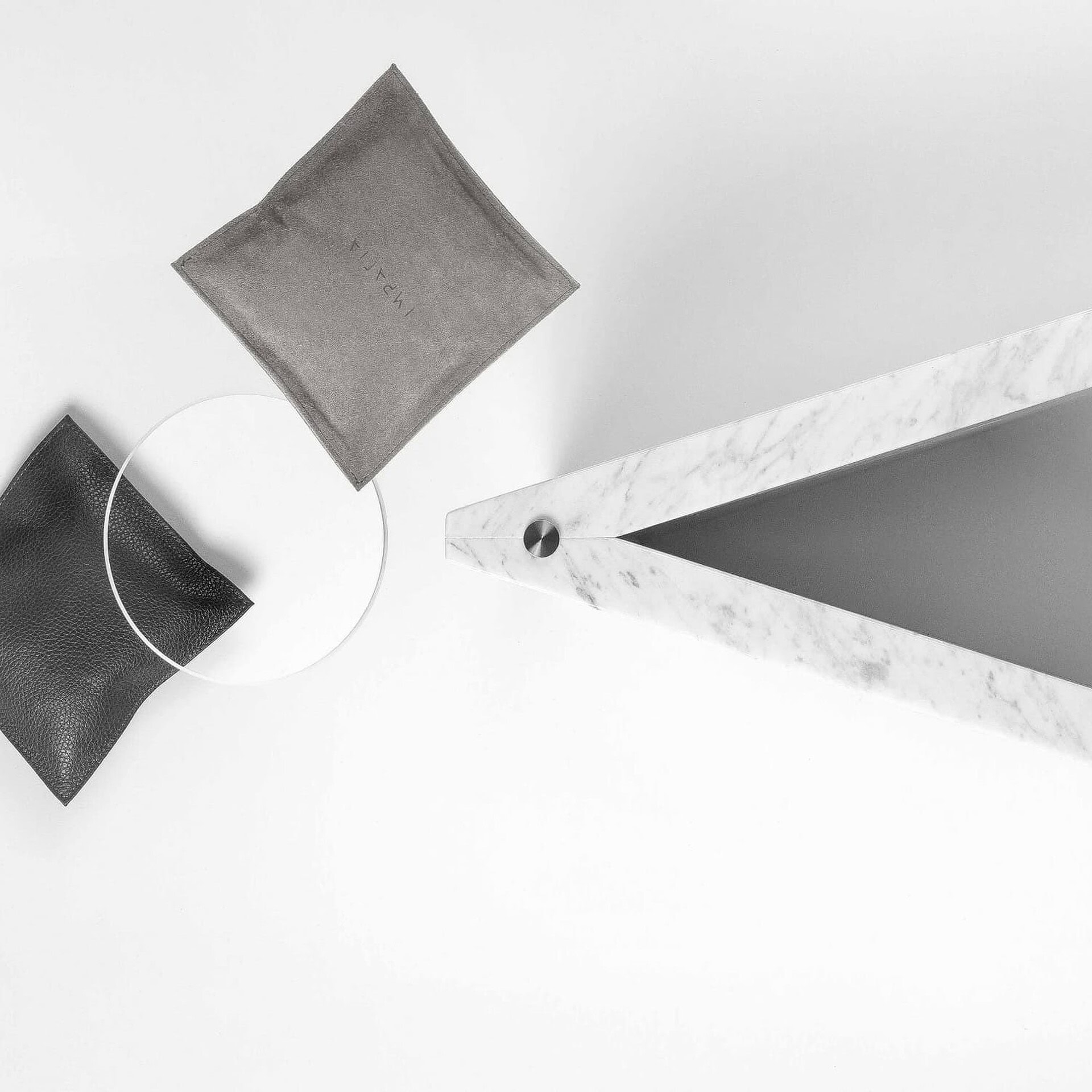 Black and gray leather pillows with a sleek marble table on a white background.