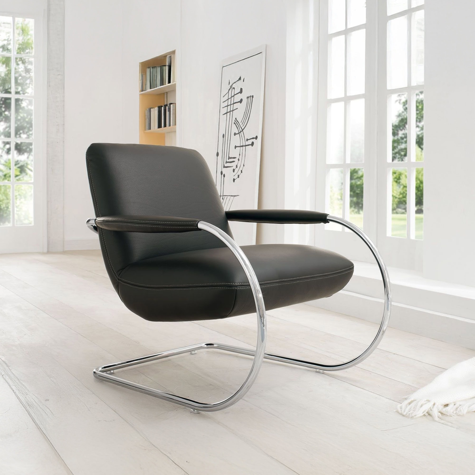 Elegant Koinor lounge chair with sleek black leather and modern chrome frame.