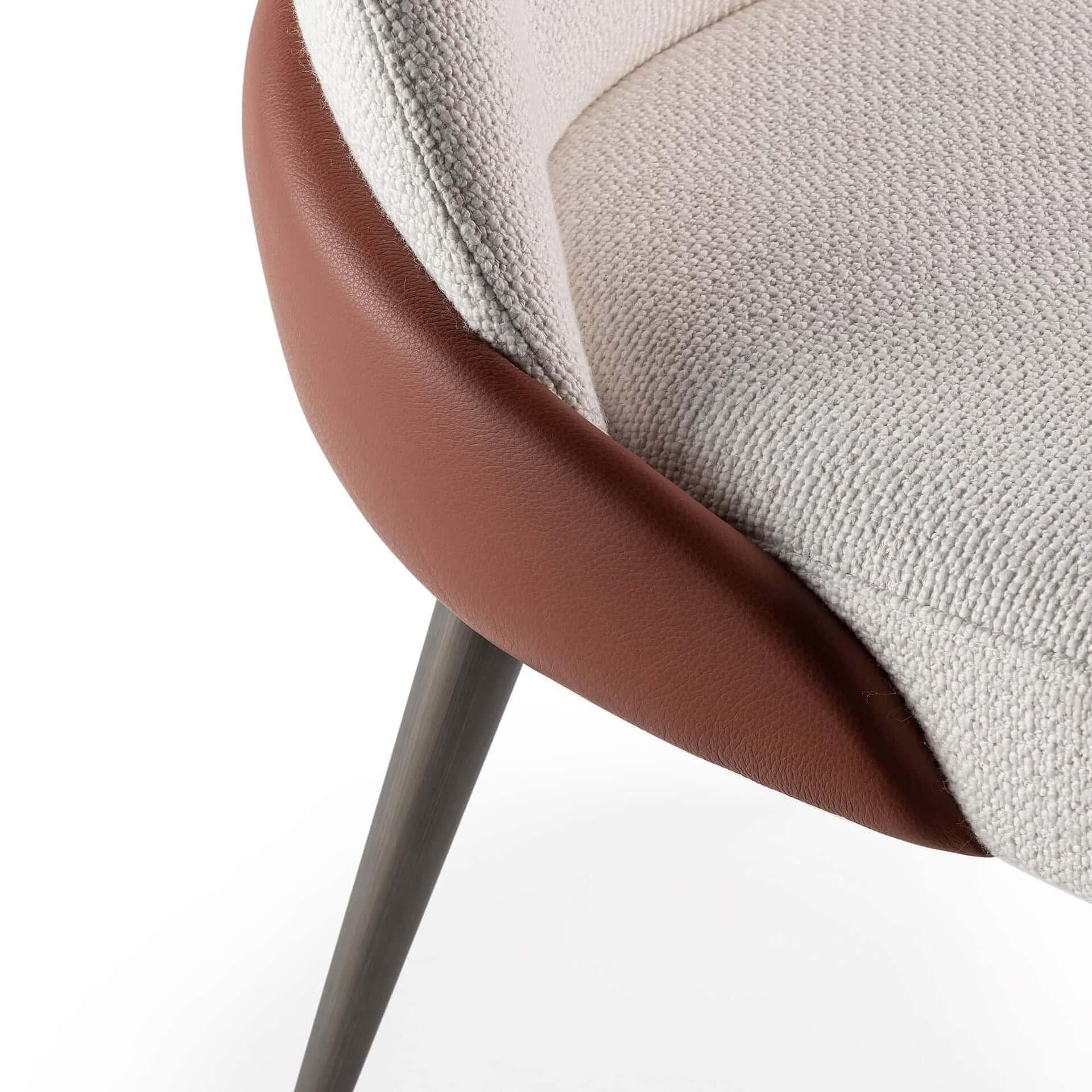 Contemporary accent chair with beige fabric upholstery and brown leather trim.