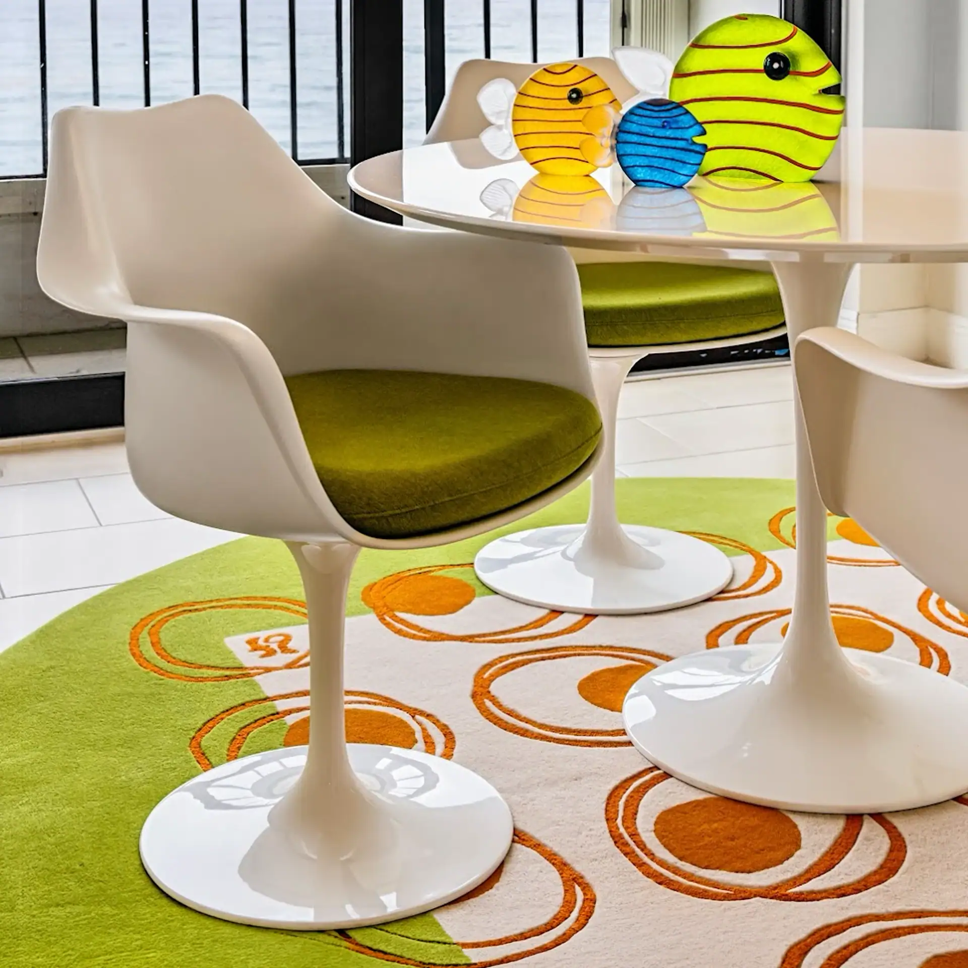 Modern White Dining Chairs with Green Cushions and Colorful Decor Contemporary white dining chairs with green cushions and vibrant decorative vases on a round table.