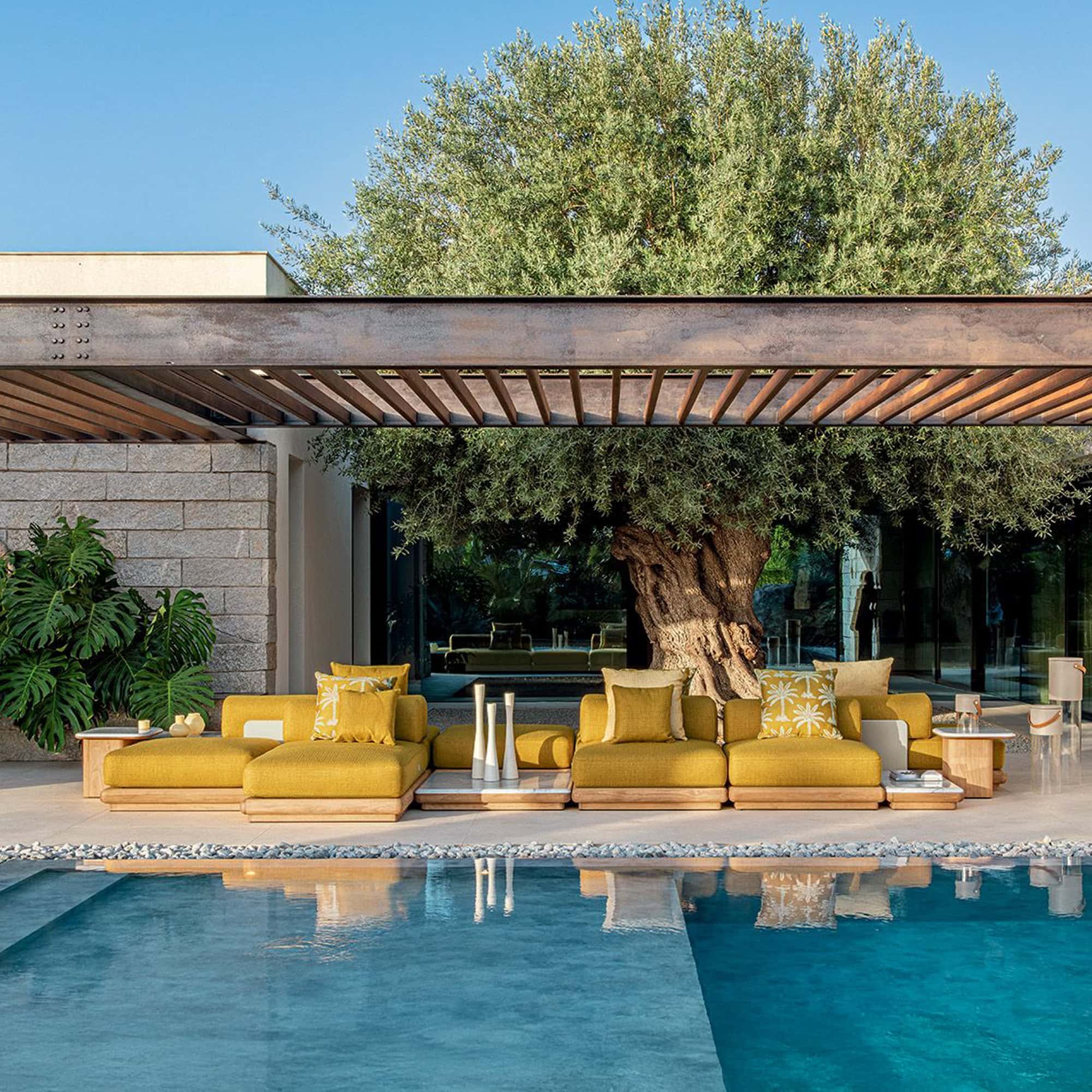 Outdoor poolside lounge with yellow cushioned seating and lush greenery.