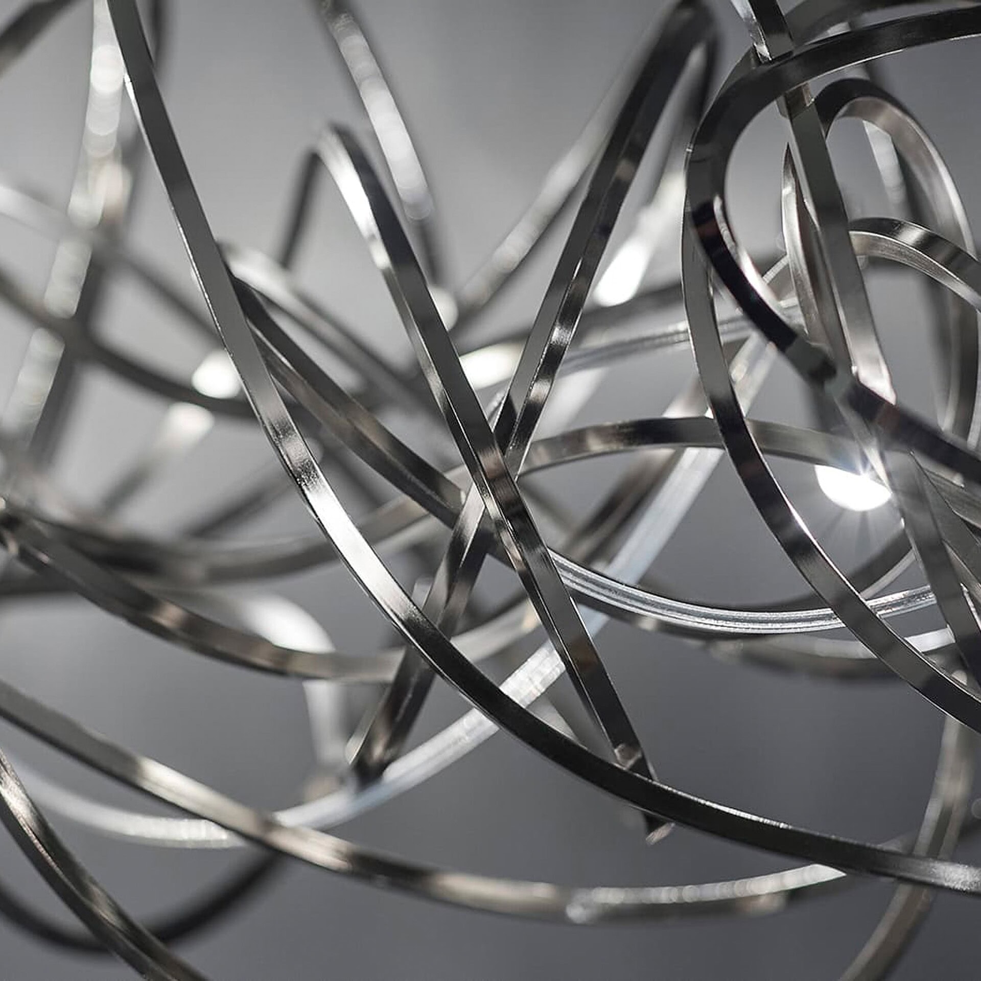 Close-up detail of the Terzani Doodle Linear Chandelier’s polished brass loops with reflective nickel finish.