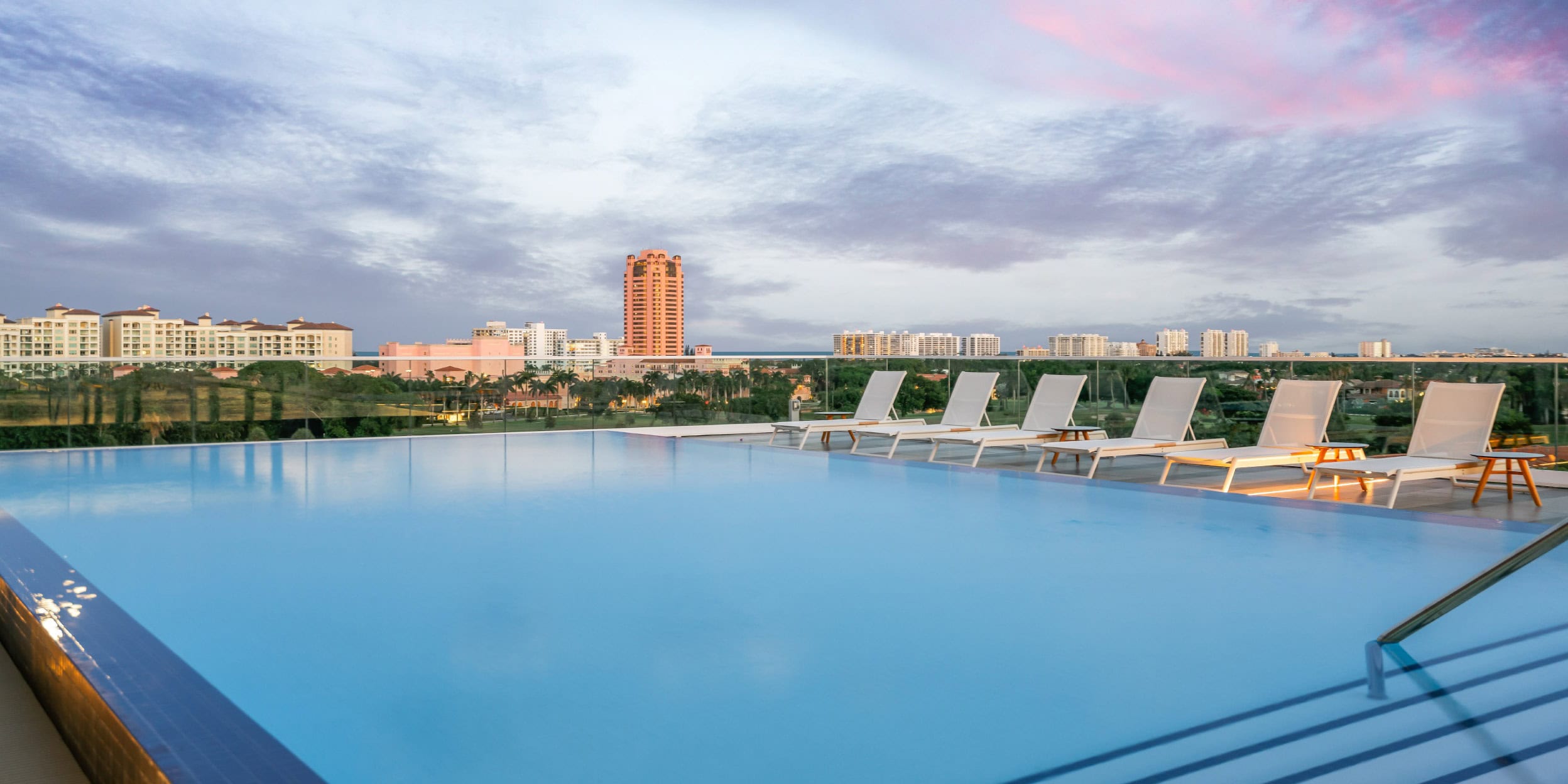 a pool with chairs and a city in the background