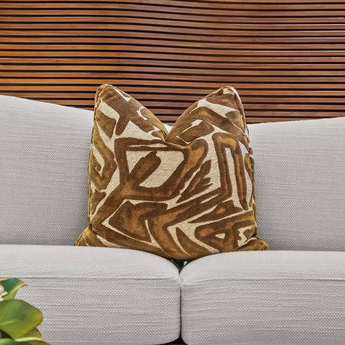 Decorative brown patterned throw pillow on a modern white sofa.
