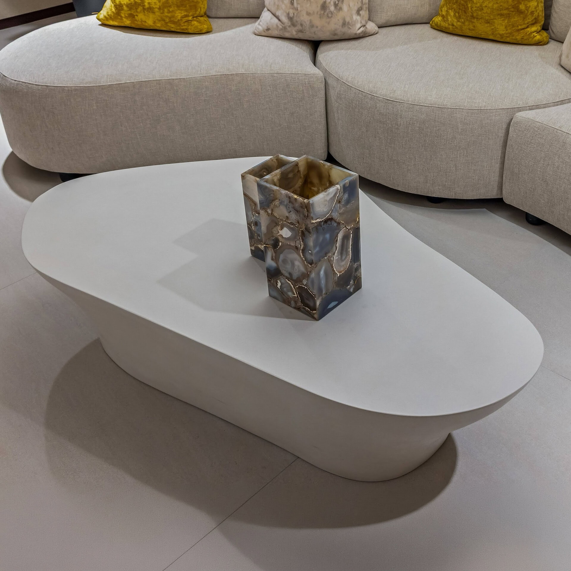 Contemporary oval coffee table with a decorative marble vase in a stylish living room setting.