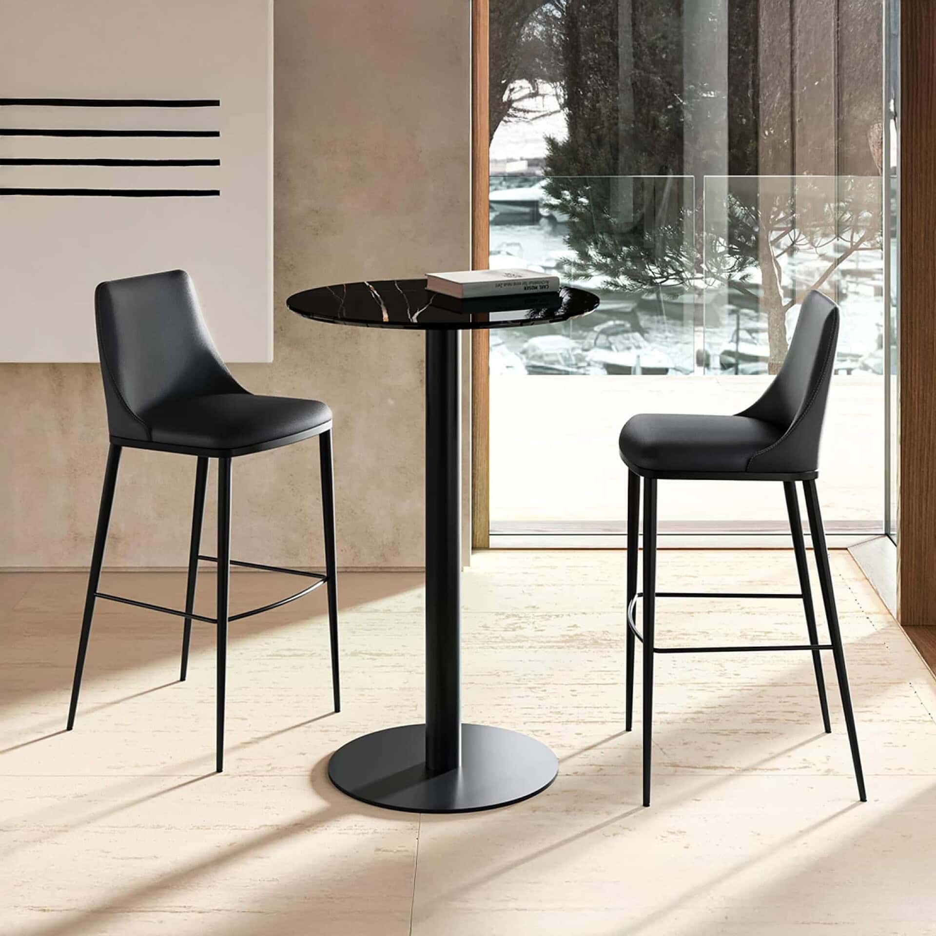 Black bar stools with leather upholstery and sleek metal legs in modern dining setting.