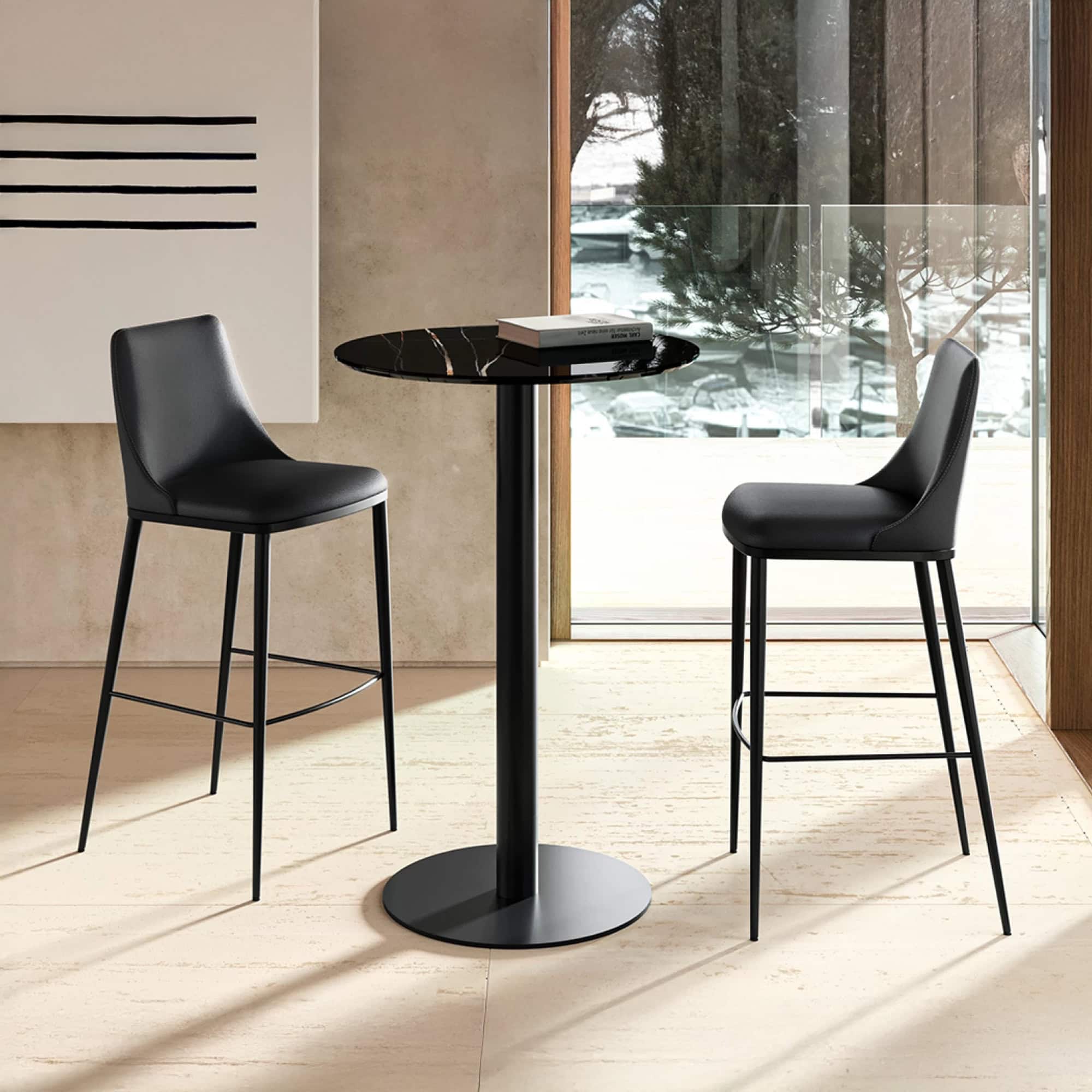 Black bar stools with leather upholstery and sleek metal legs in modern dining setting.