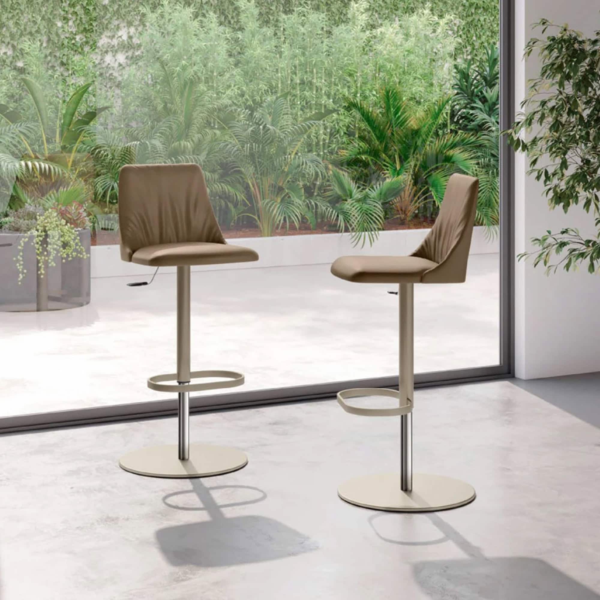 Contemporary beige height-adjustable bar stools with leather seats and footrests in modern interior setting.