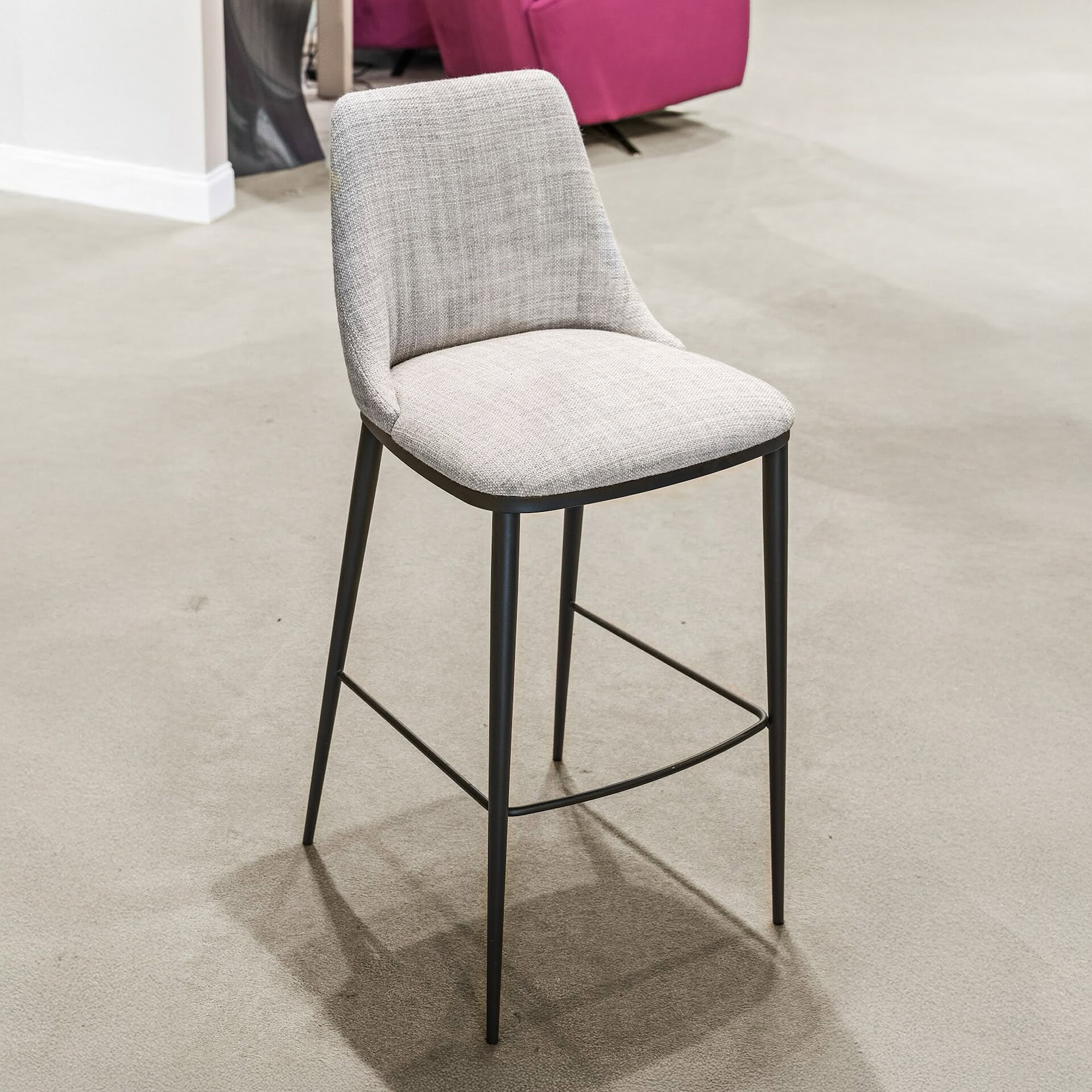 Contemporary upholstered bar stool with black metal legs and footrest, ideal for modern kitchen or bar area.