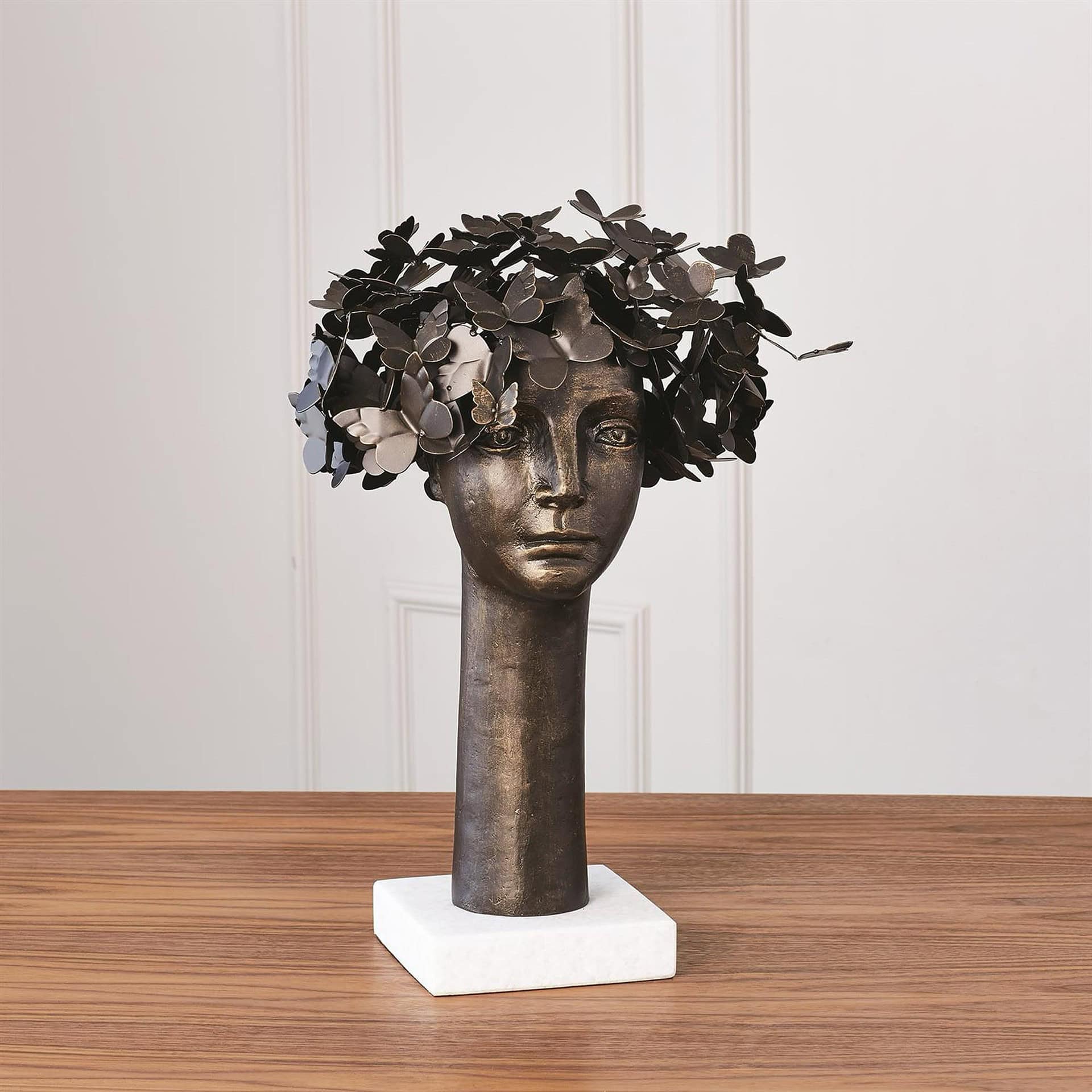 A bronze sculpture of a woman's head with flowers.