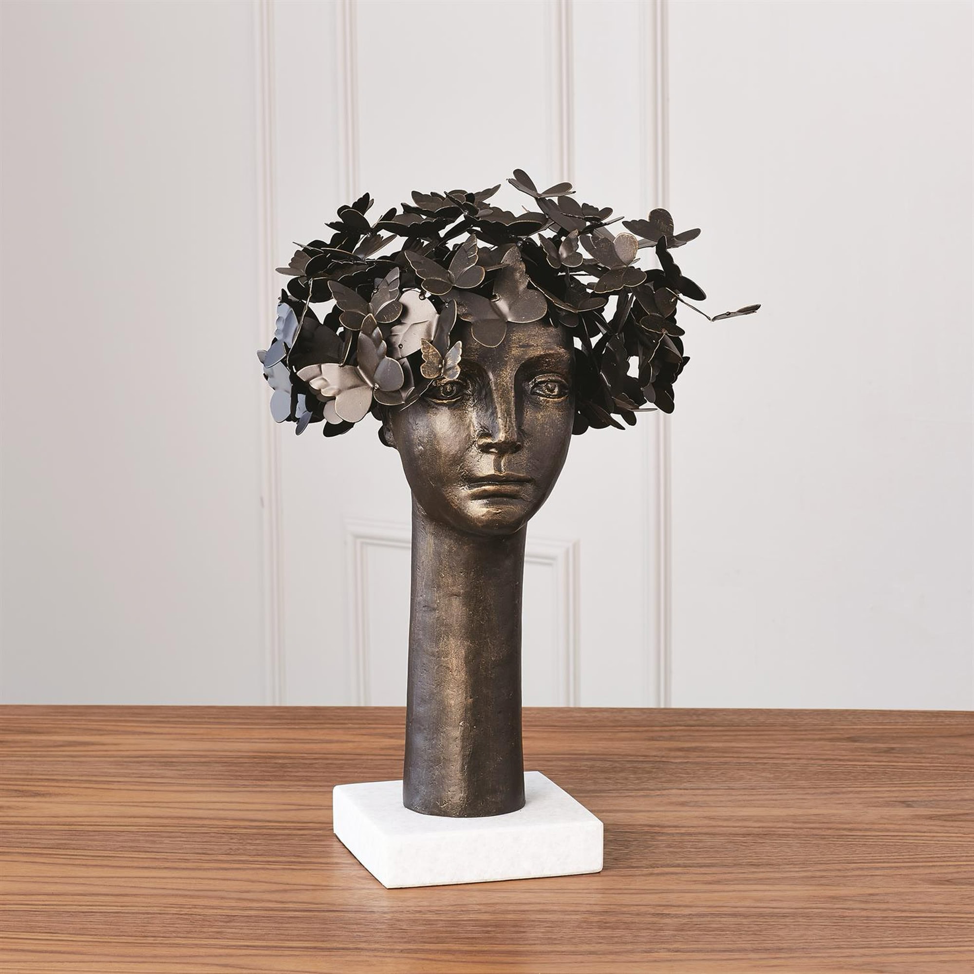 A bronze sculpture of a woman's head with flowers.