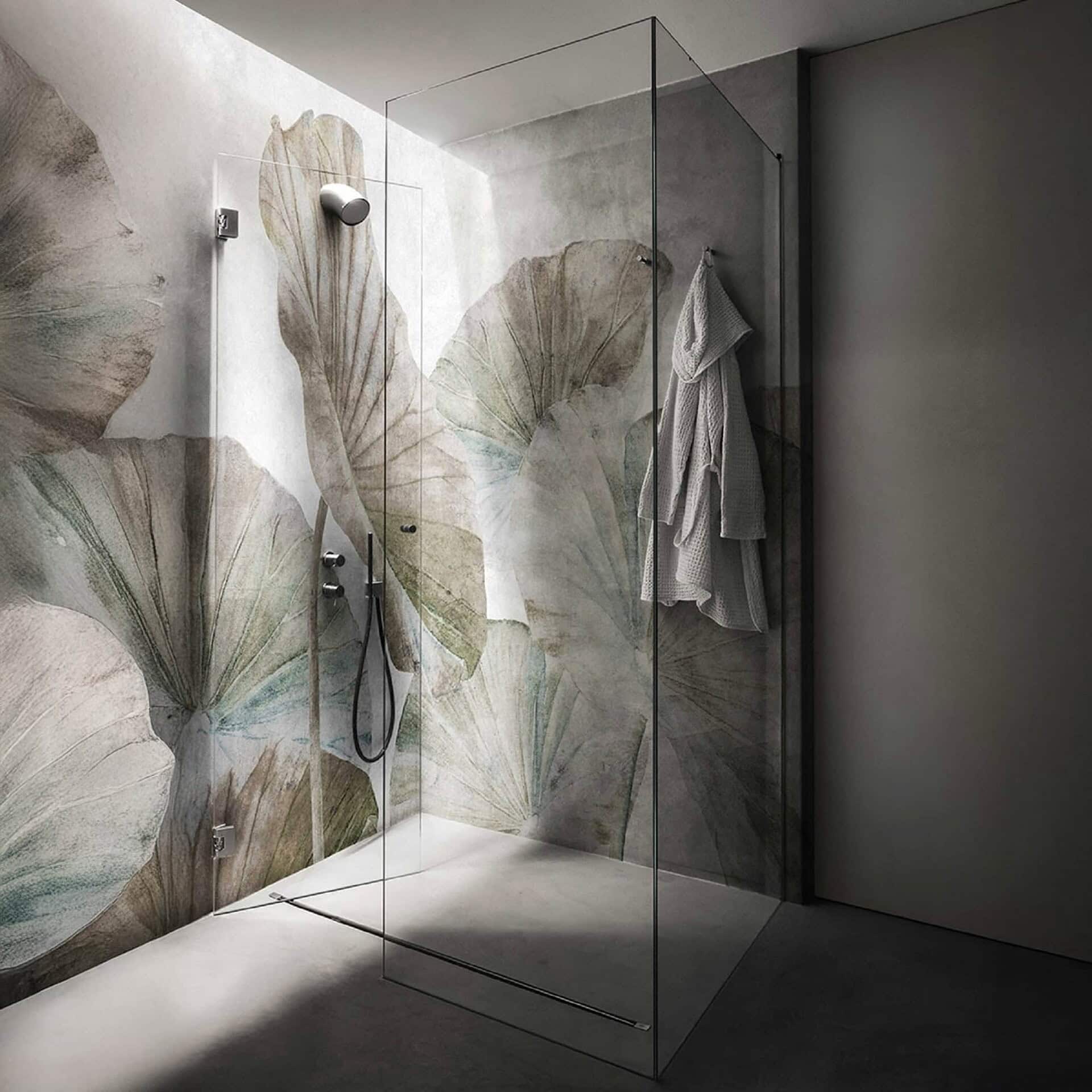 Bathroom interior with Naiadi Wallpaper in earthy neutrals — oversized botanical leaf motifs in soft green and beige tones surrounding a glass shower enclosure.