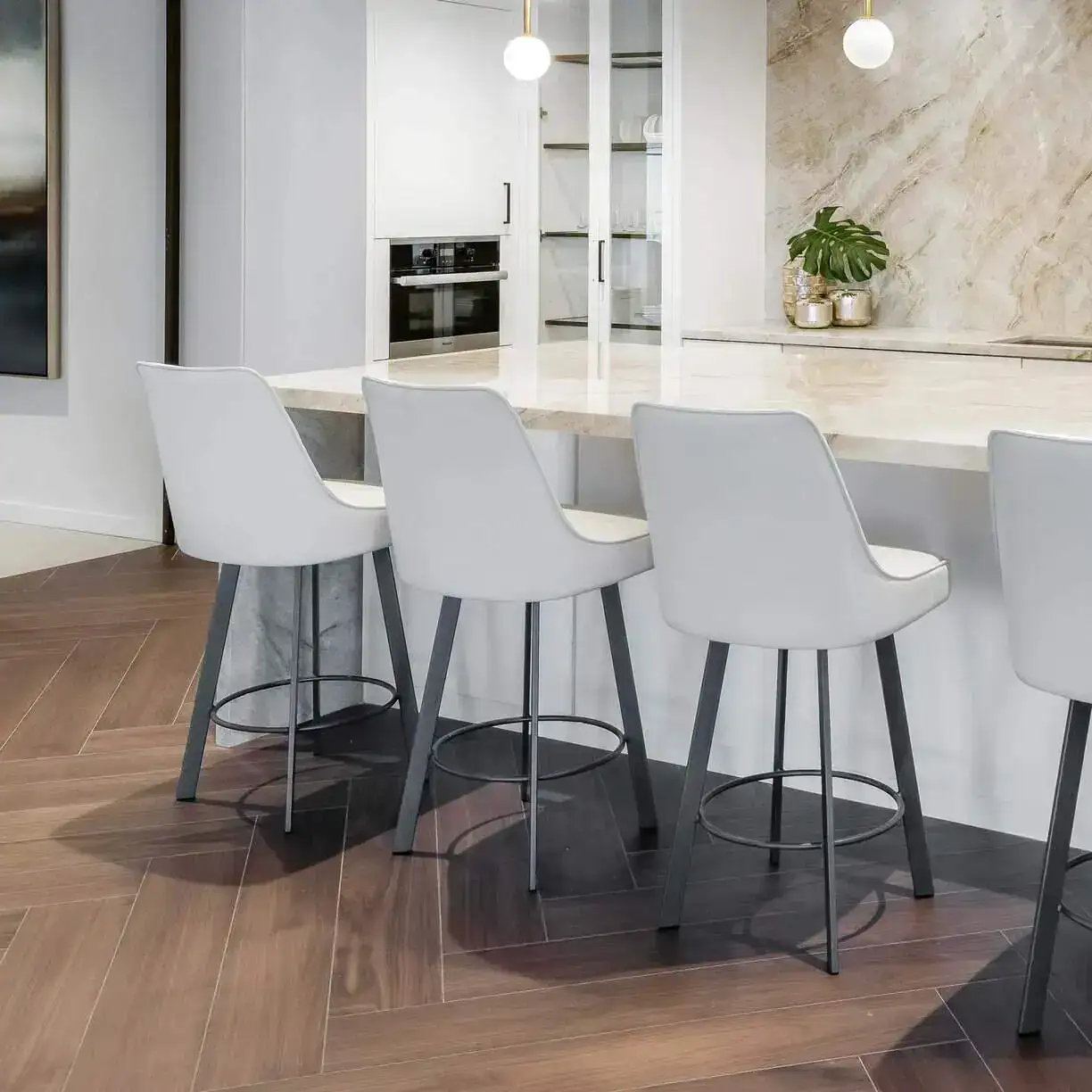 a white kitchen with white chairs and a marble counter