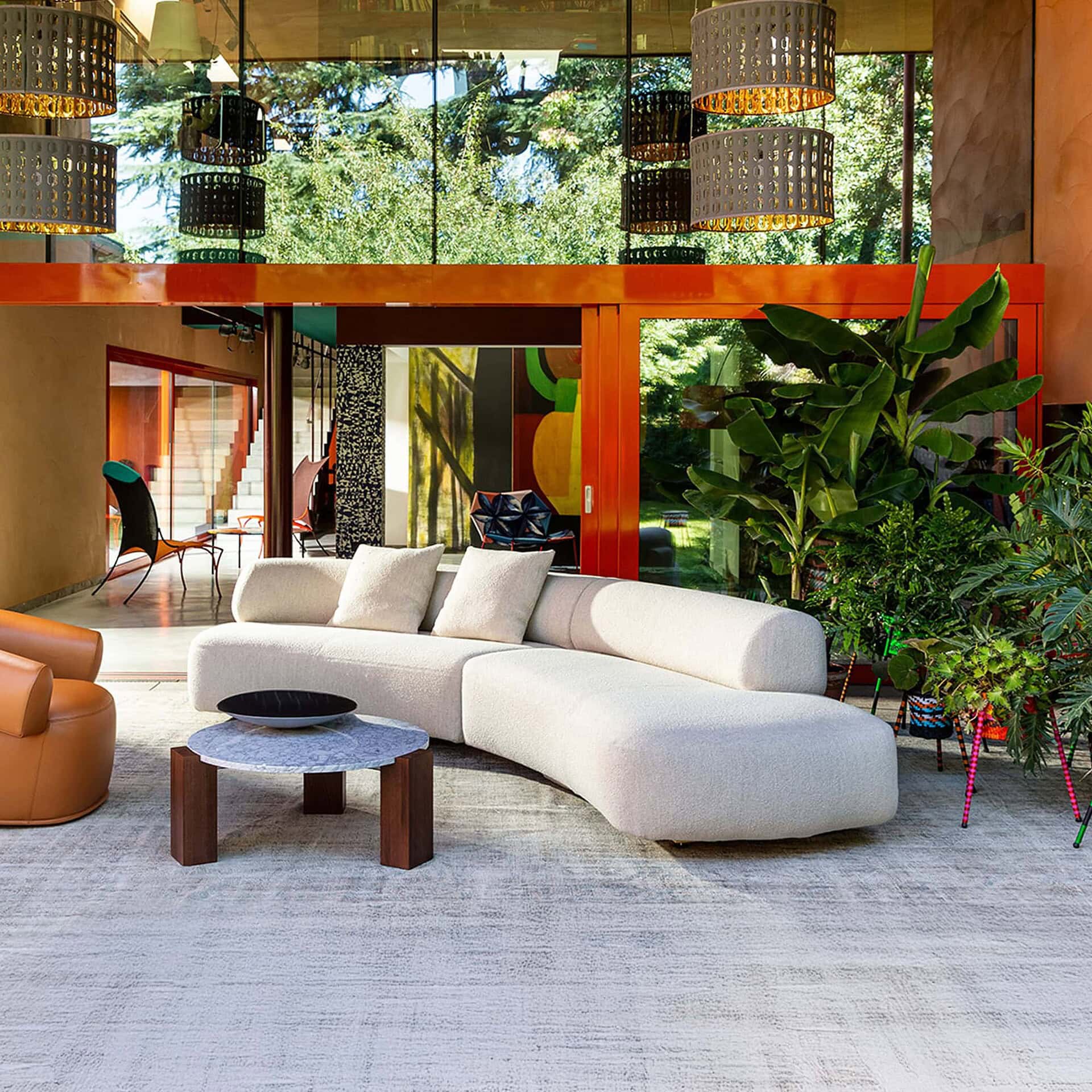 Outdoor-inspired setting with the Gogan Modular Curved Sofa in a cream upholstery, paired with a glass coffee table.