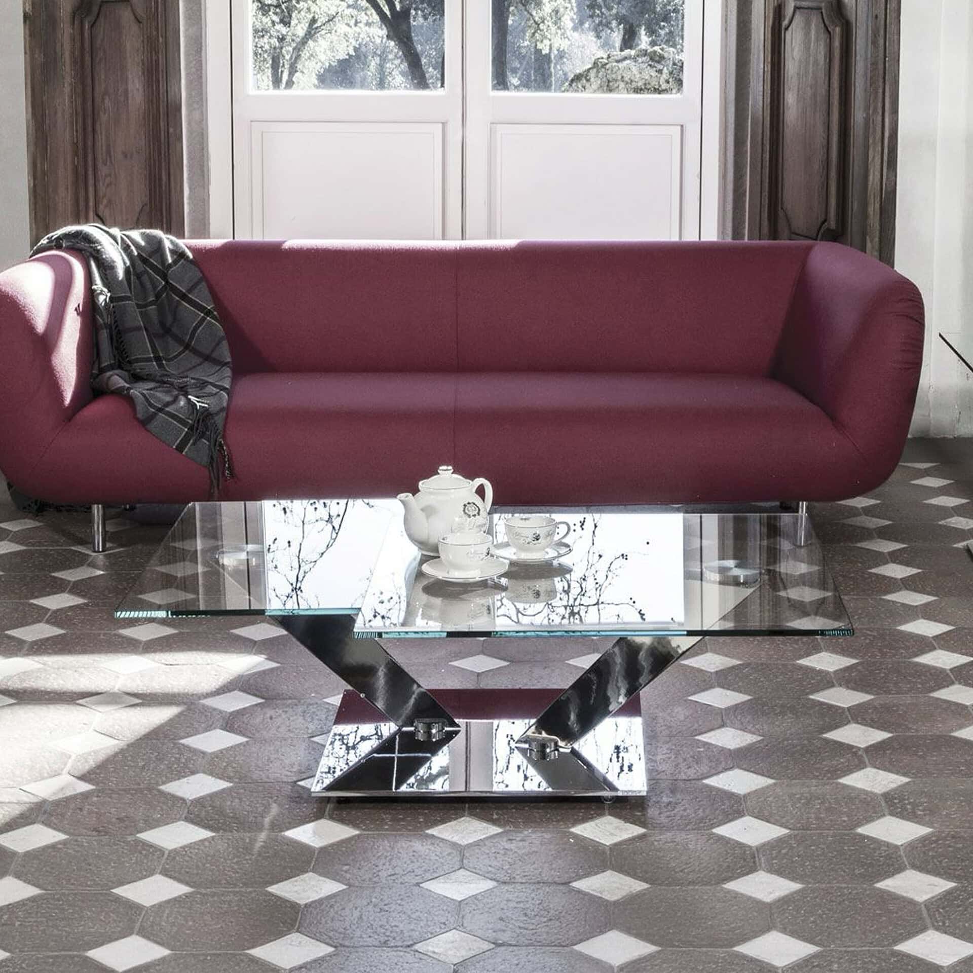 Maroon sofa with sleek glass coffee table in contemporary living room setting.