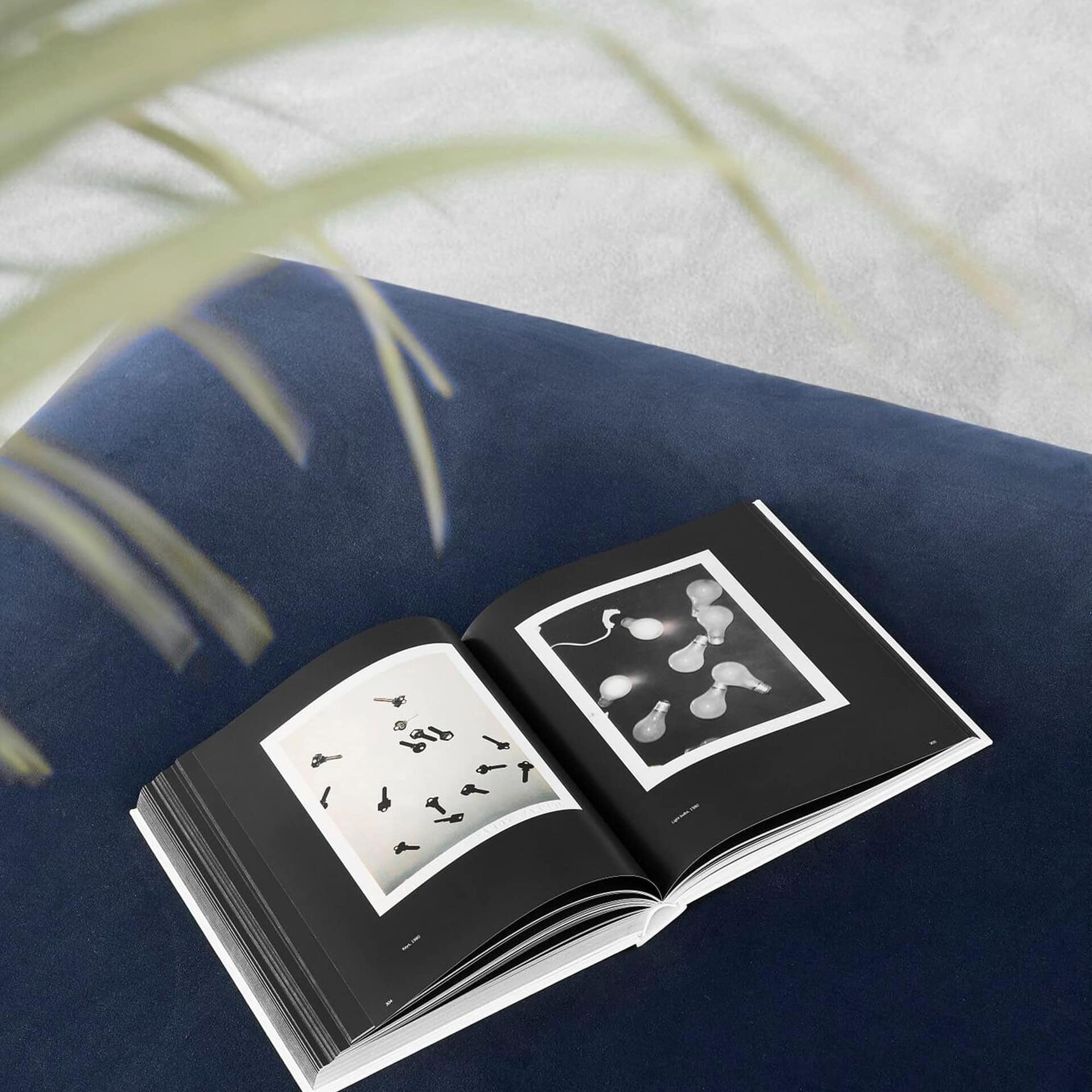 Close-up view of the Main Square Ottoman in blue fabric with an open book placed on top.