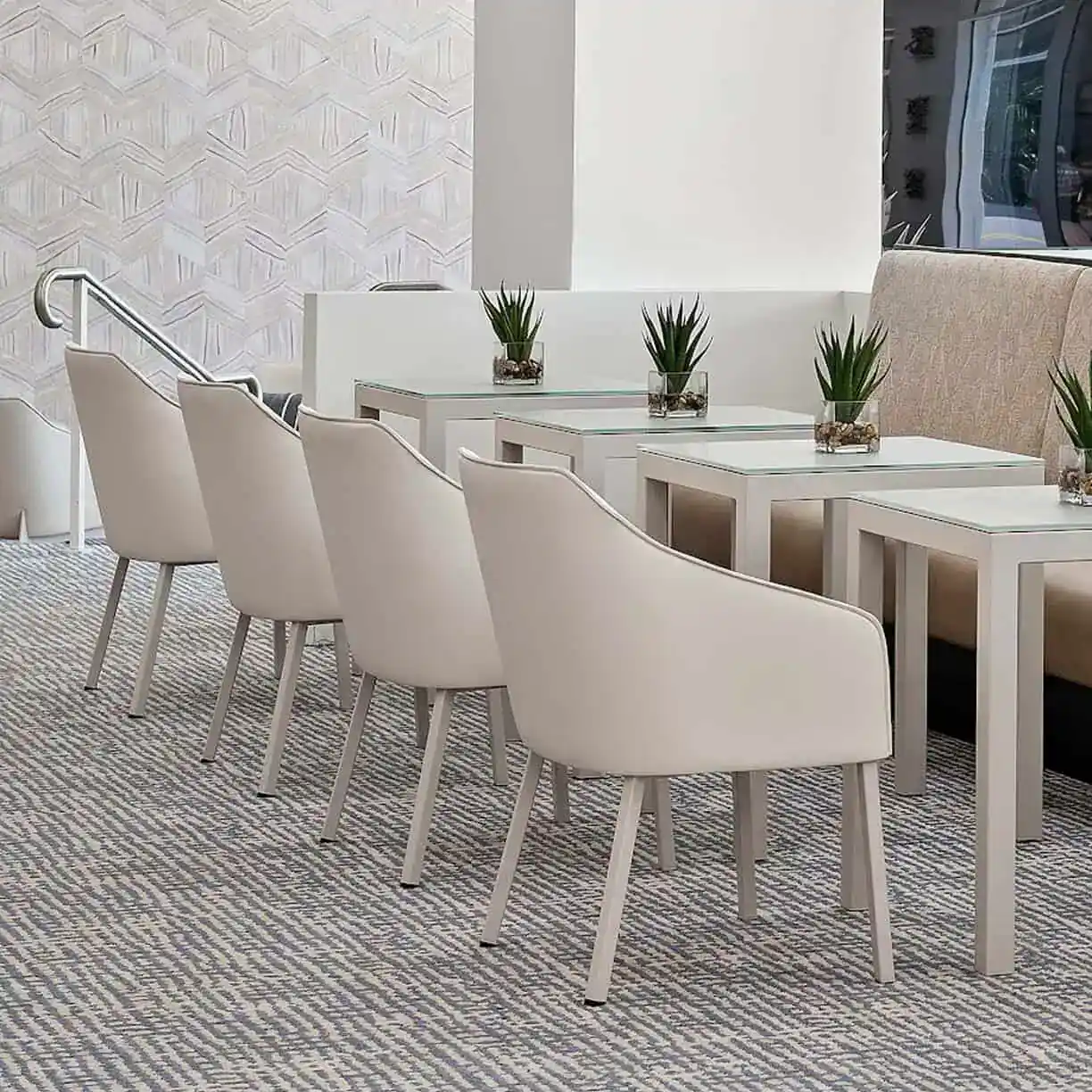 A Group Of White Chairs And Tables In A Room