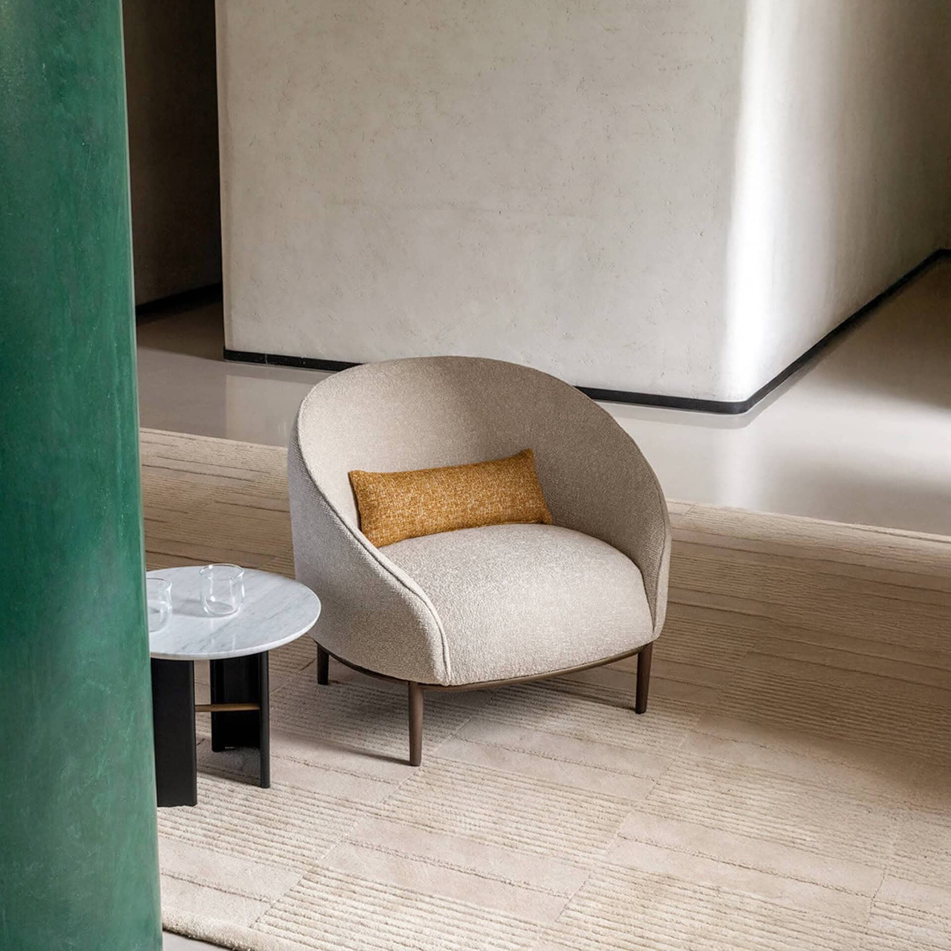 Yoisho Upholstered Armchair in modern living room with round side table and yellow accent pillow.