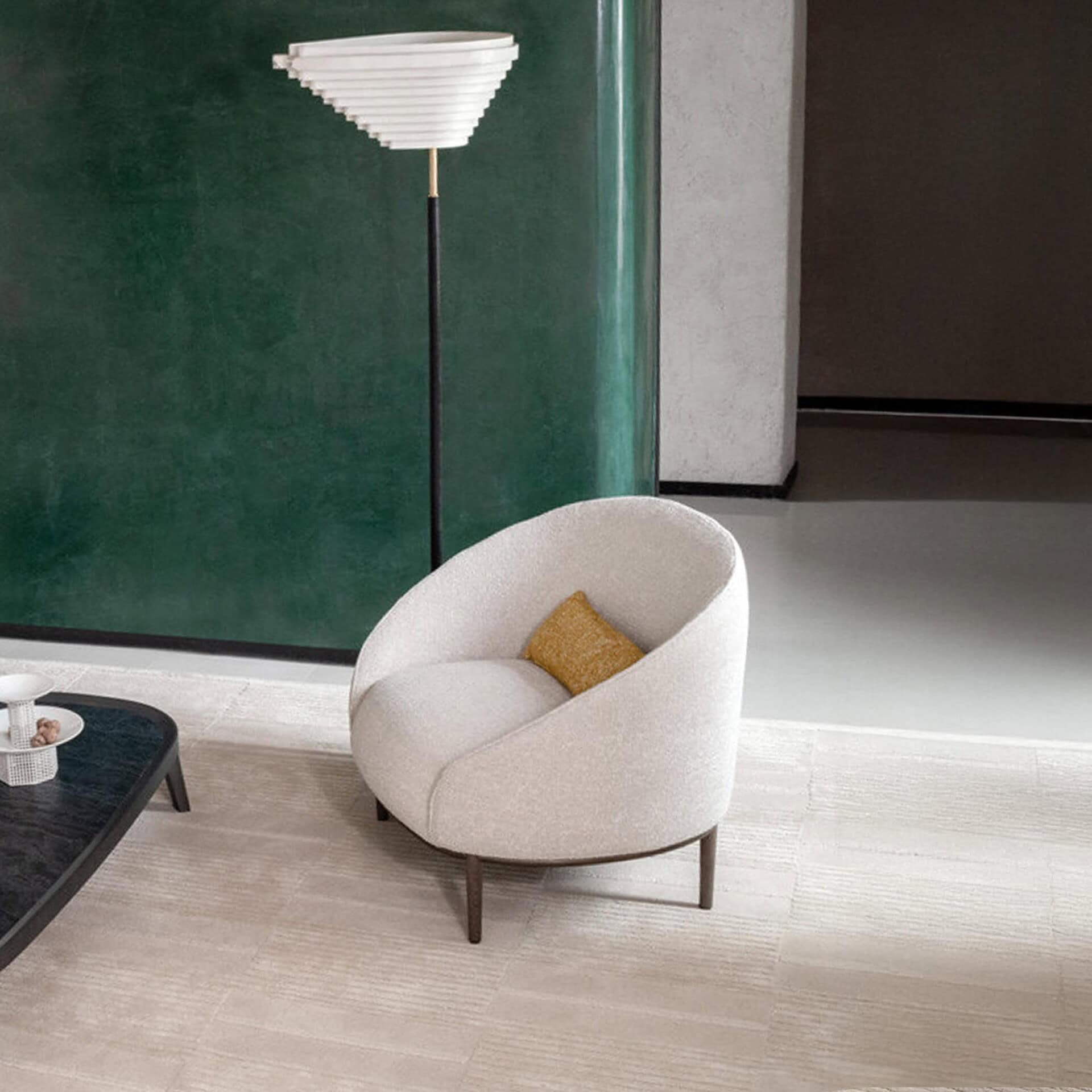 Yoisho Upholstered Armchair in neutral setting with curved silhouette and bronze base.