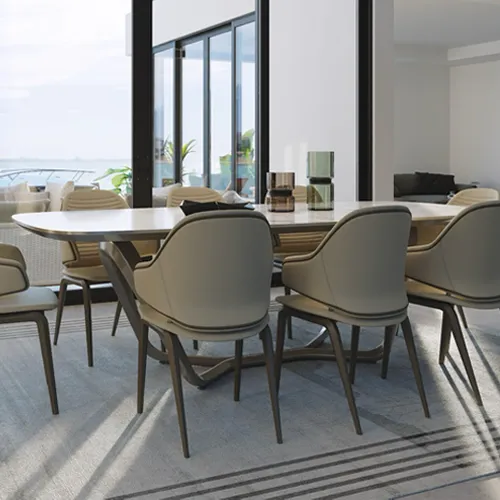 A modern dining room with a large light table, beige upholstered chairs, and floor-to-ceiling windows offering a view of water and a boat.