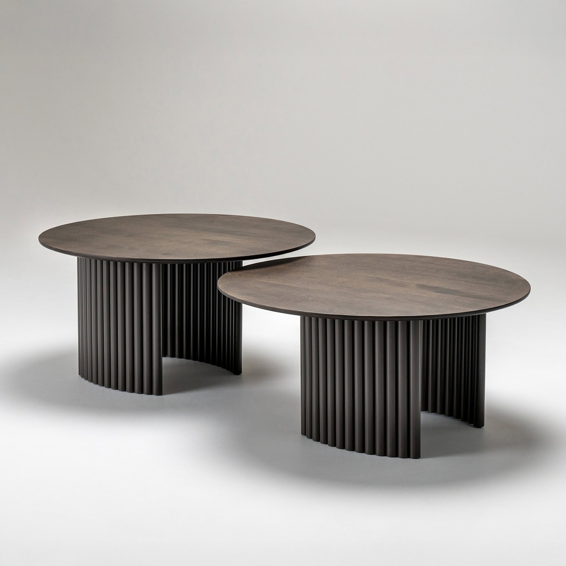 Set of two Cove Round Coffee Tables with round tops and sculptural fluted bases in a dark wood finish.