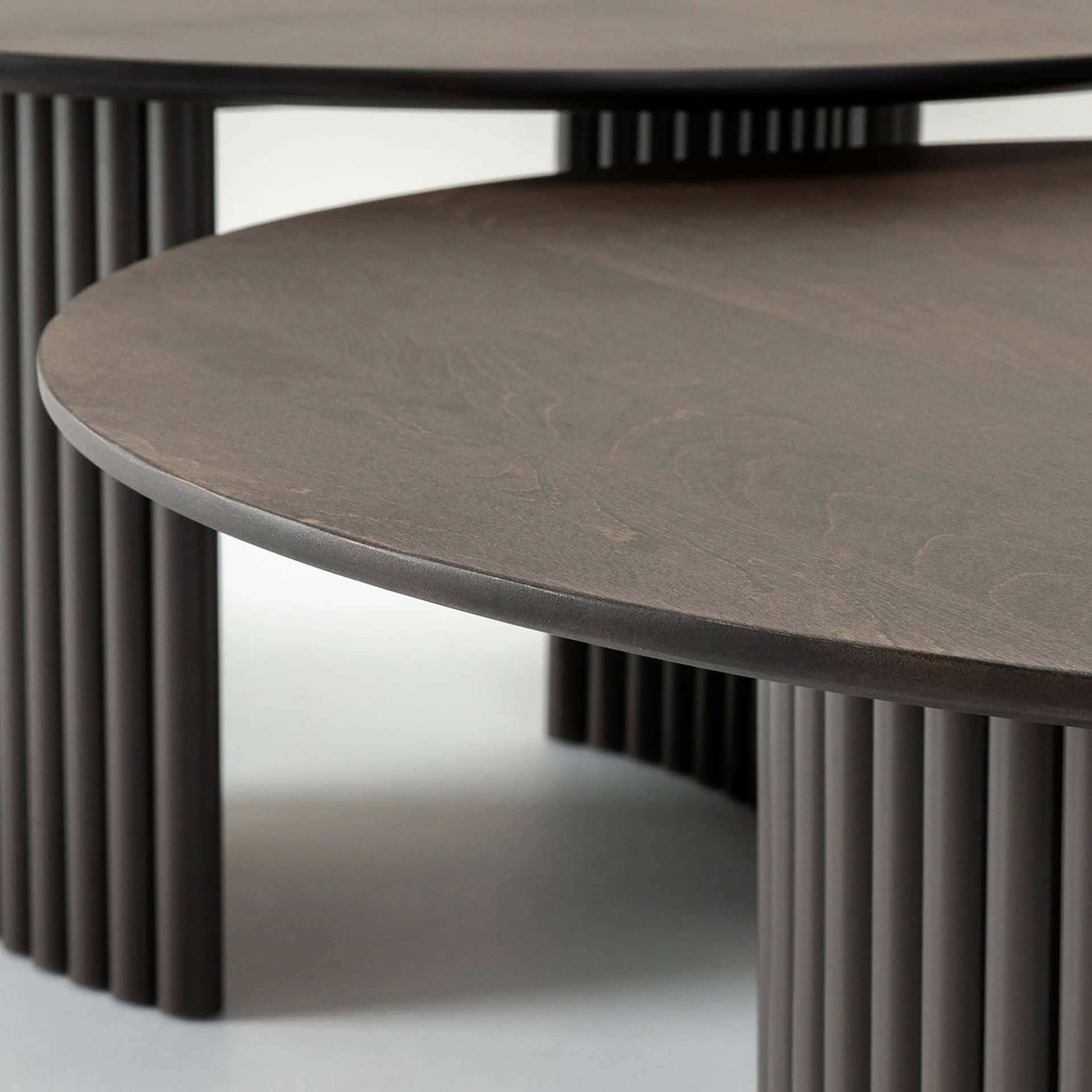 Close-up of the Cove Round Coffee Table showing the smooth wood top and textured fluted base construction.